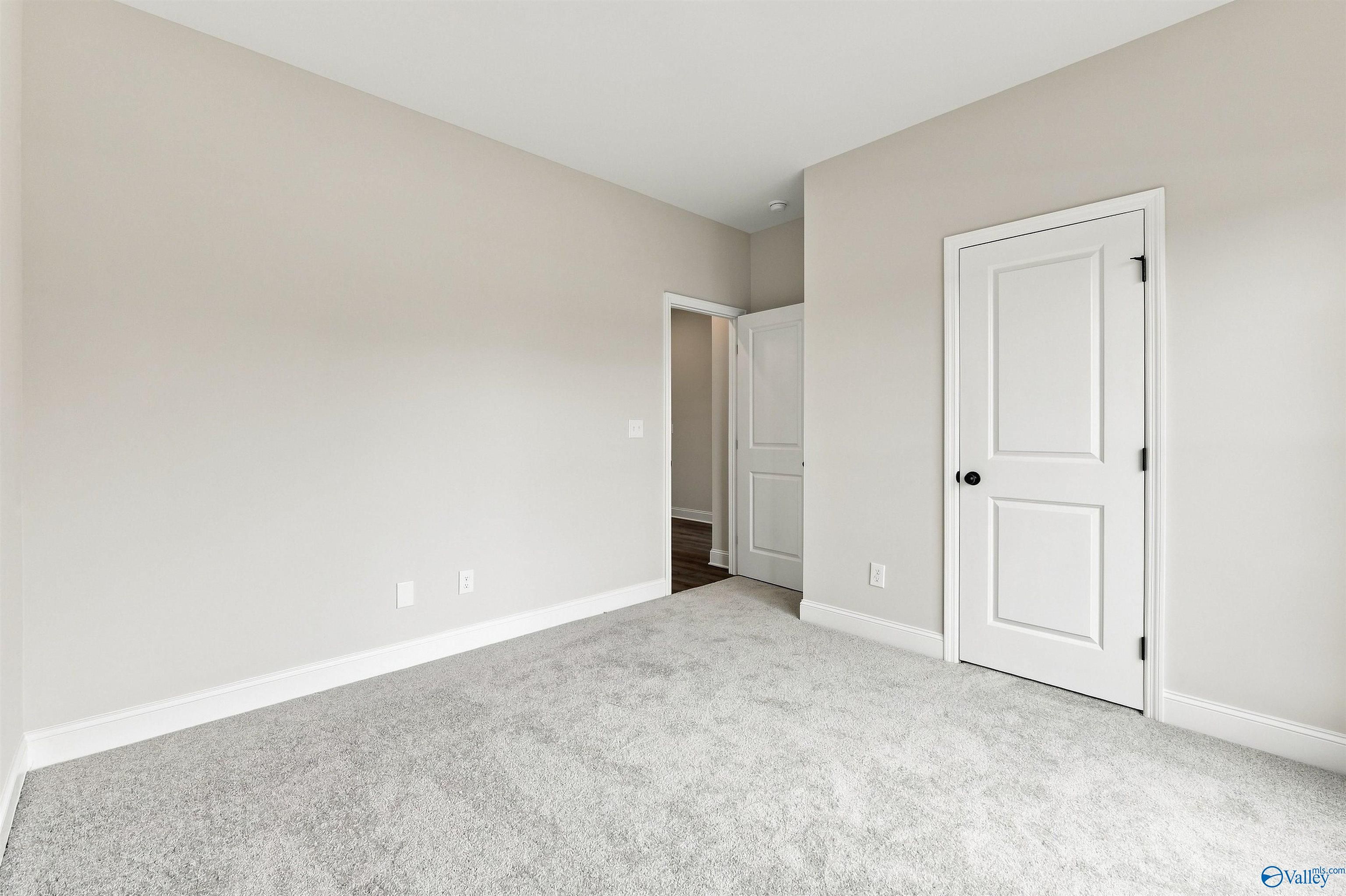 Spacious carpeted bedroom with neutral walls and white doors in Davidson Homes' Franklin C plan, The Meadows, Athens, Alabama