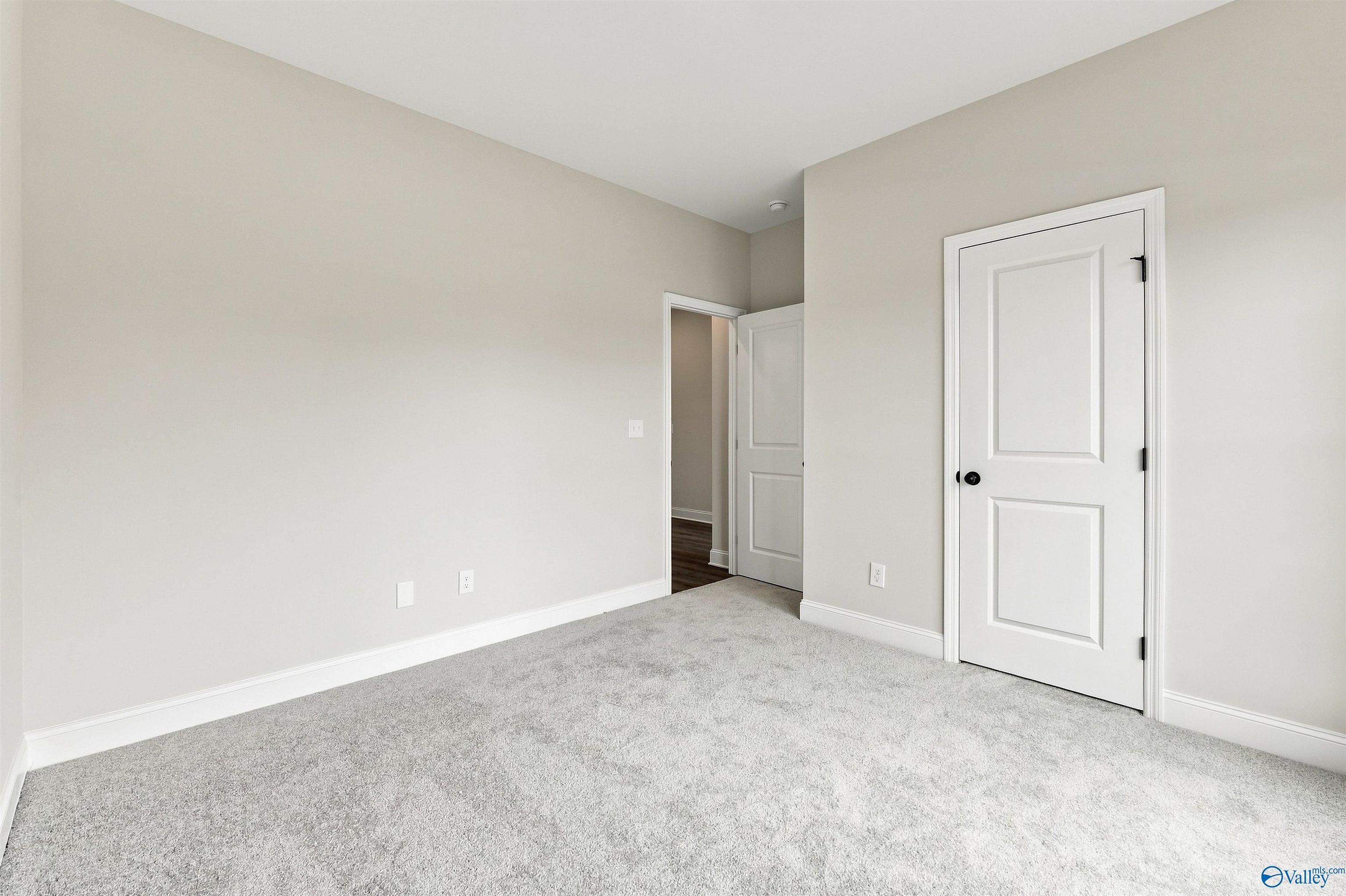 Spacious carpeted bedroom with neutral walls and white doors in Davidson Homes' Franklin C plan, The Meadows, Athens, Alabama