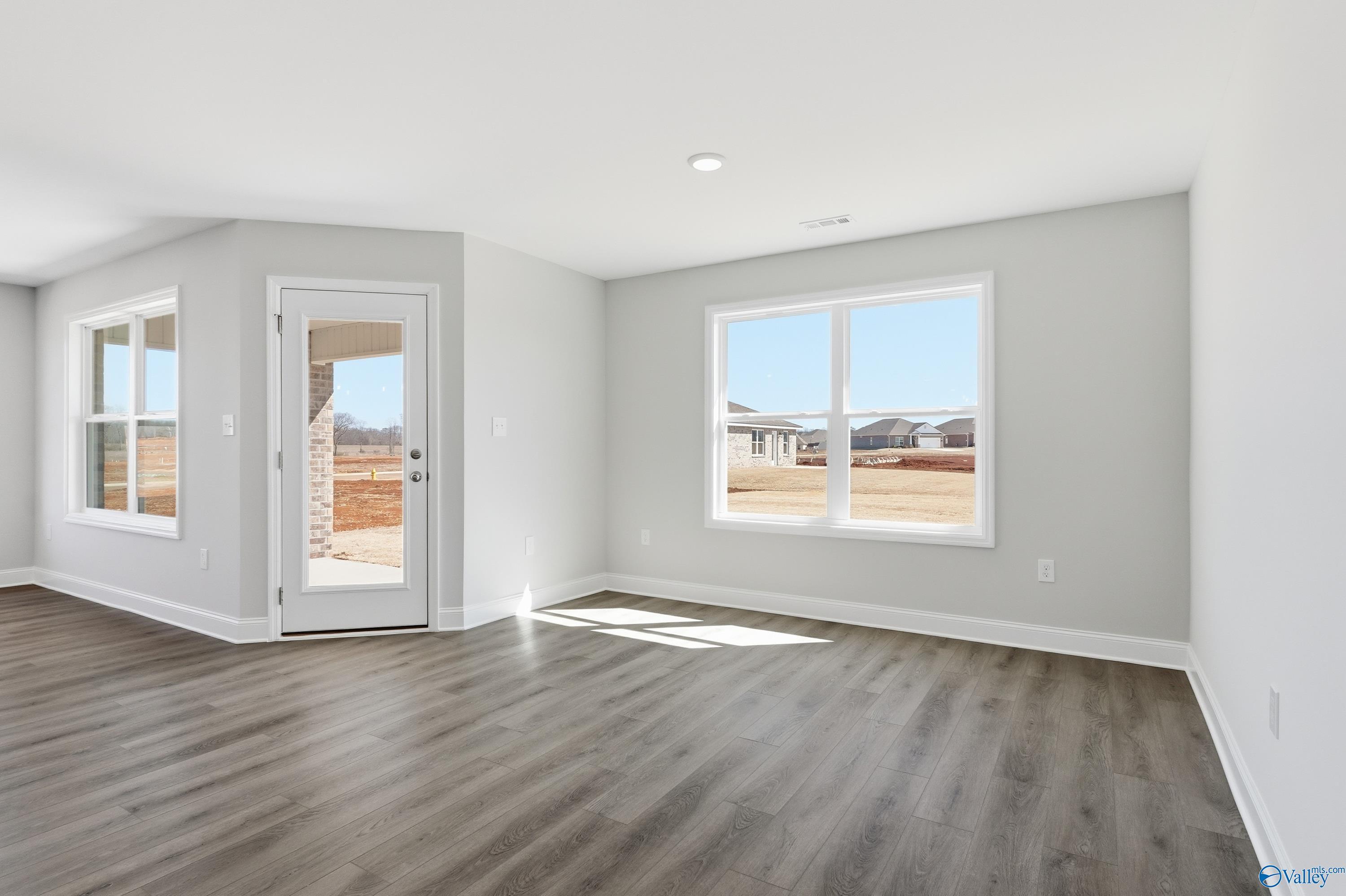 Bright living room with gray walls, large windows, French doors to patio, luxury vinyl flooring in Davidson Homes The Franklin, New Market, AL