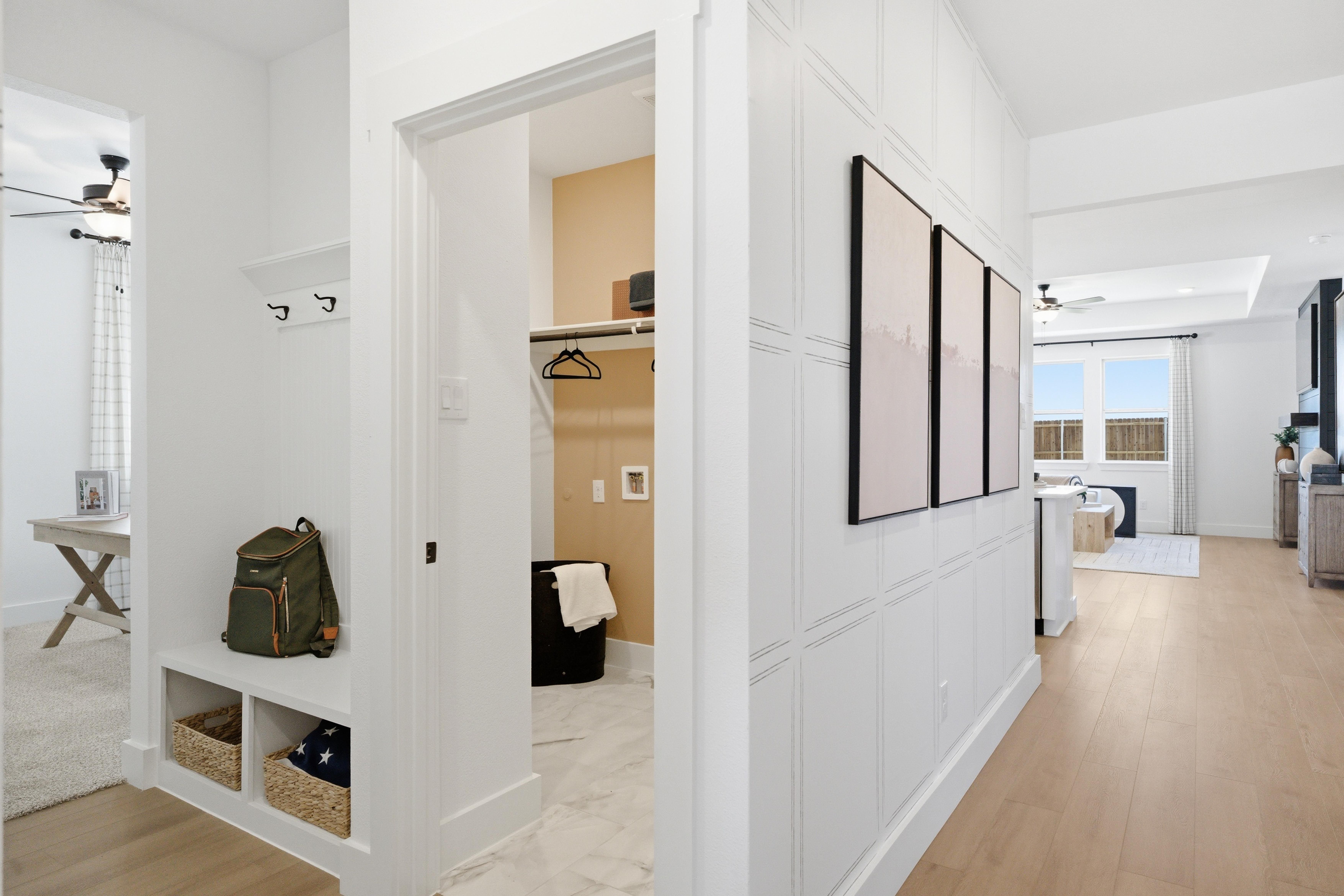 Spacious mudroom at Mercer Meadows in Royse City, Texas with white shiplap walls, built-in storage, coat hooks, laundry nook and light oak floors