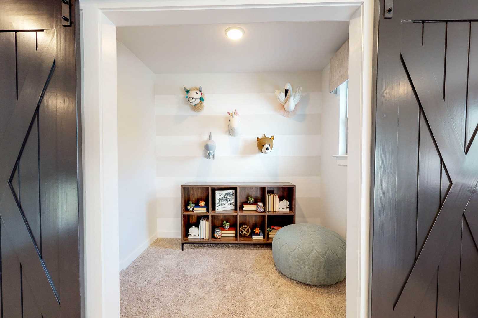 Charming nursery with plush animal wall hangings, toy-filled bookshelf, and blue pouf in Liberty Creek, Gallatin TN by Davidson Homes