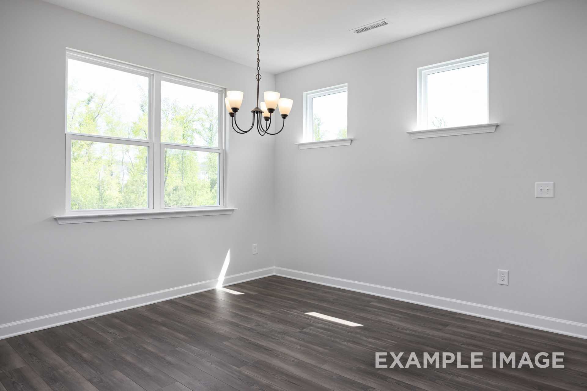 Bright living room in The Grace C Davidson Homes with gray walls, large sunny windows, hardwood floors, and elegant chandelier