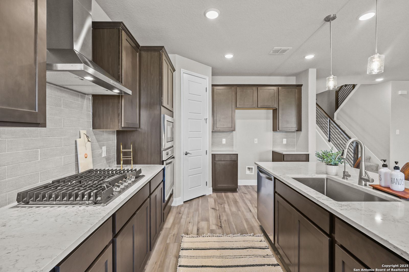 Modern kitchen with dark wood cabinets, quartz counters, stainless appliances, subway tile in Jennings G by Davidson Homes, Castroville TX