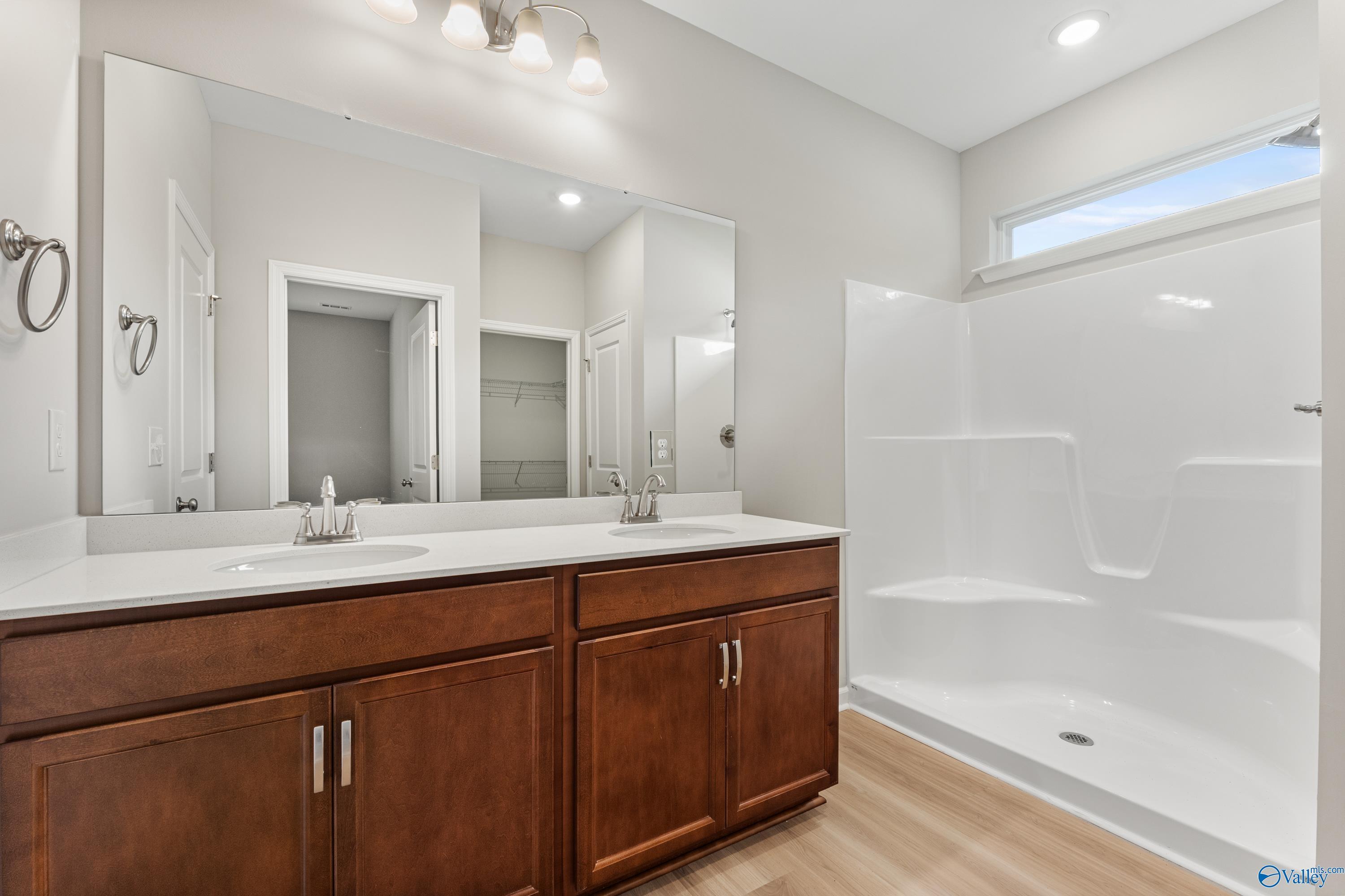 Modern master bathroom featuring double vanity with wood cabinets, tiled walk-in shower, and large mirror in Davidson Homes The Aurora, Fayetteville, TN