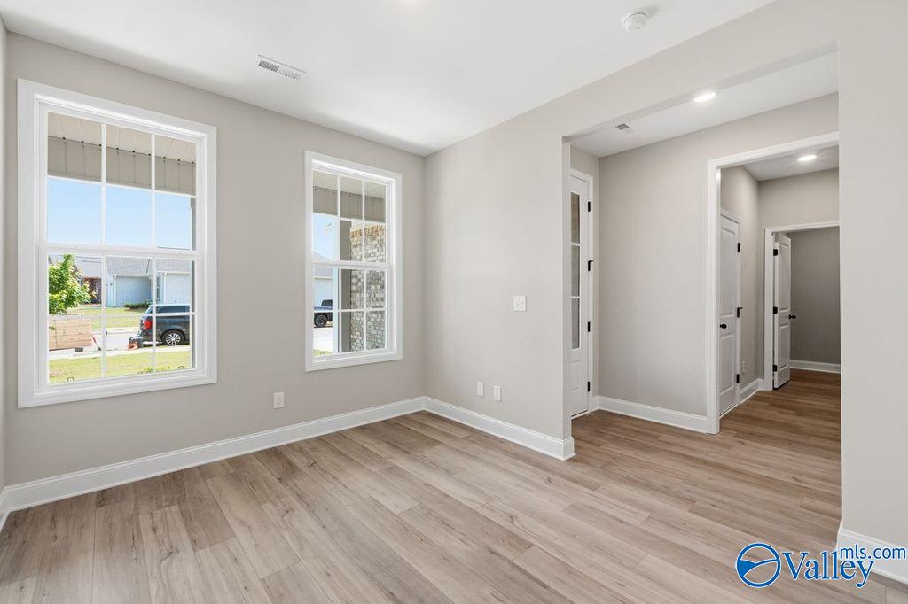 Bright living room with large windows overlooking yard, light gray walls, hardwood floors in Davidson Homes The Rockford, Hartselle AL