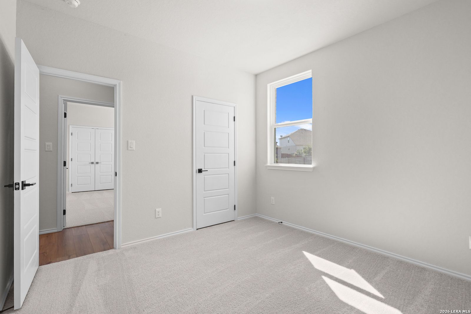 Bright carpeted bedroom with white doors and sunny window in Davidson Homes Glenwood E plan at Comanche Ridge, San Antonio