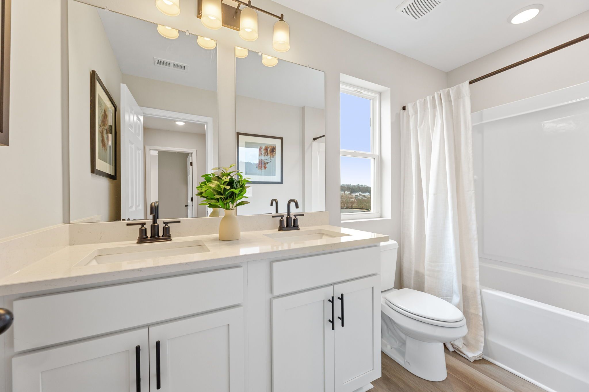 Modern bathroom in Hemingway Cumming GA featuring double vanity, bathtub shower, and large window by Davidson Homes
