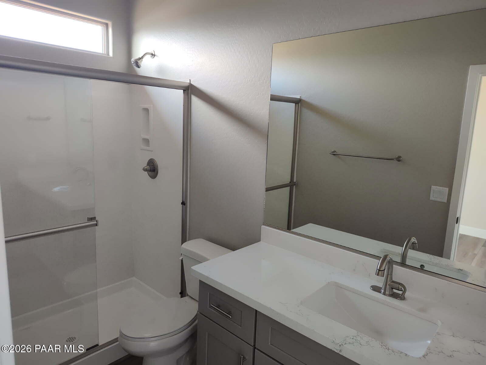 Modern bathroom with glass walk-in shower, quartz vanity, single sink, and large mirror in Davidson Homes The Harmony C, Prescott Valley, Arizona