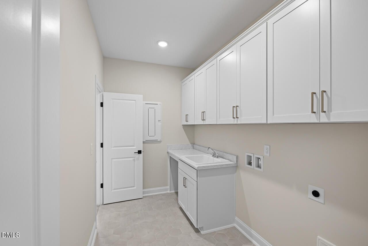 Laundry room with white cabinets, sink, and hex tile floor in Davidson Homes The Crawford D, Wake Forest, NC