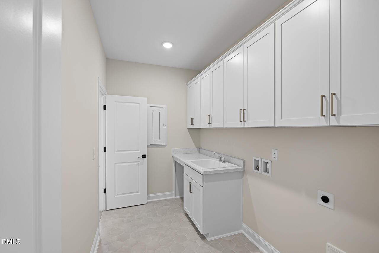 Laundry room with white cabinets, sink, and hex tile floor in Davidson Homes The Crawford D, Wake Forest, NC