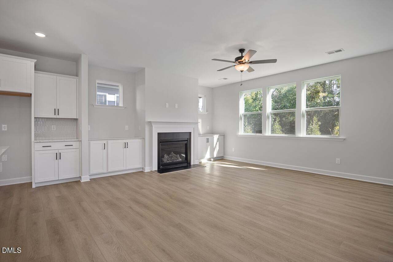 Bright open-concept great room with fireplace, white built-ins, and hardwood floors in Davidson Homes The Preston C, Wendell Ridge NC