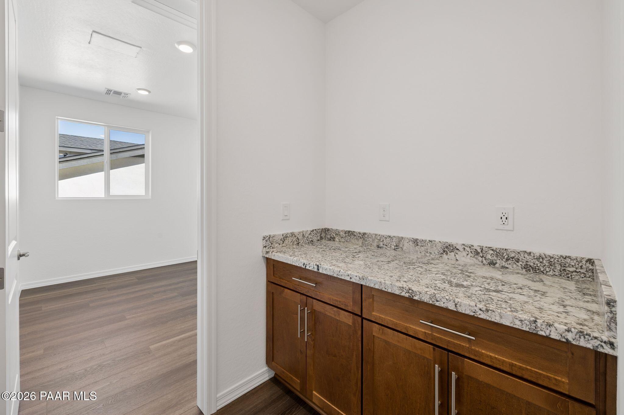 Modern laundry room with quartz countertop, wood cabinets, and ample storage in The Monarch A by Davidson Homes, Prescott, AZ