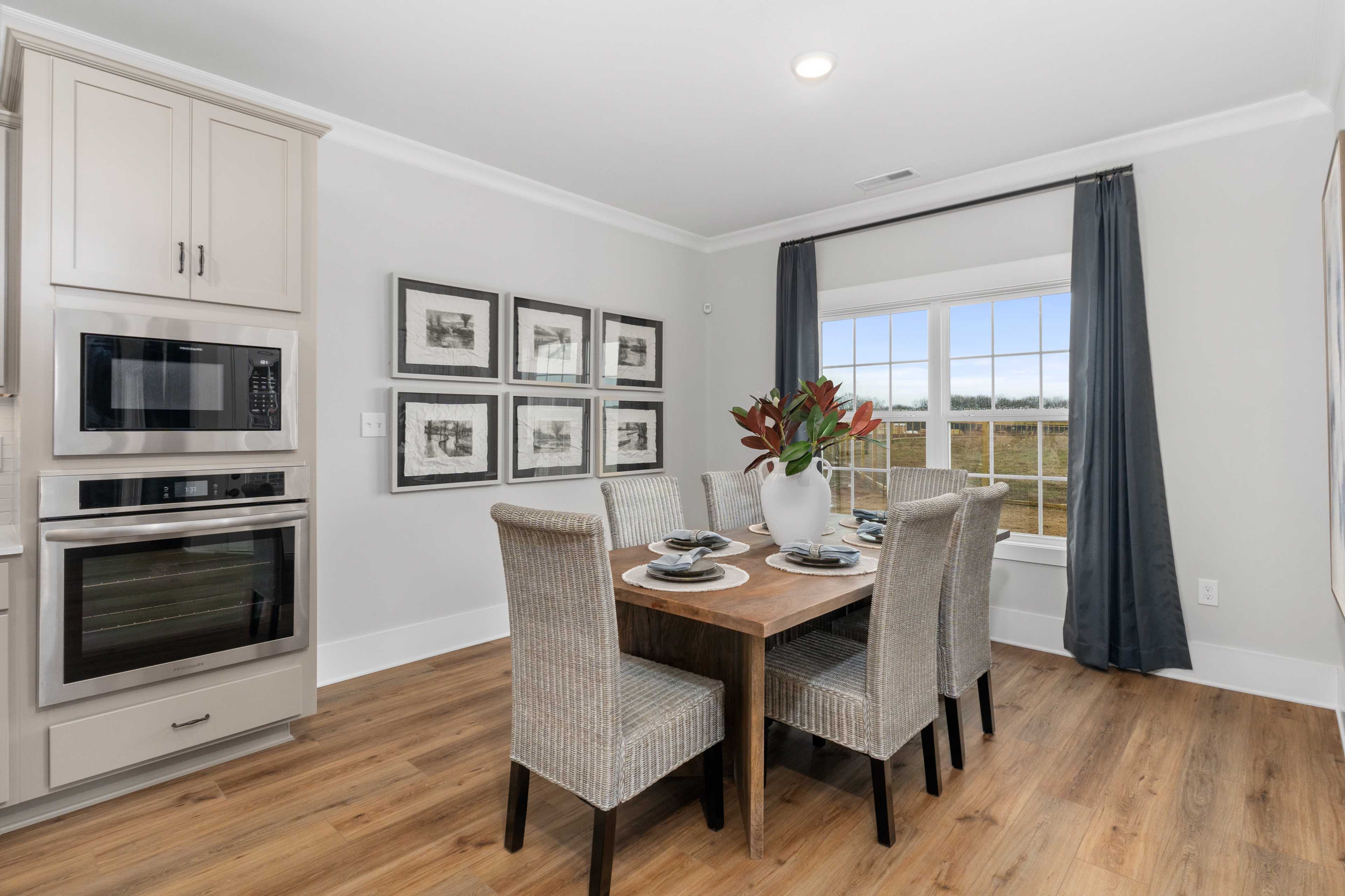 Elegant dining area in Kendall Farms home, Toney Alabama with shaker cabinets, stainless appliances, hardwood floors and scenic field view
