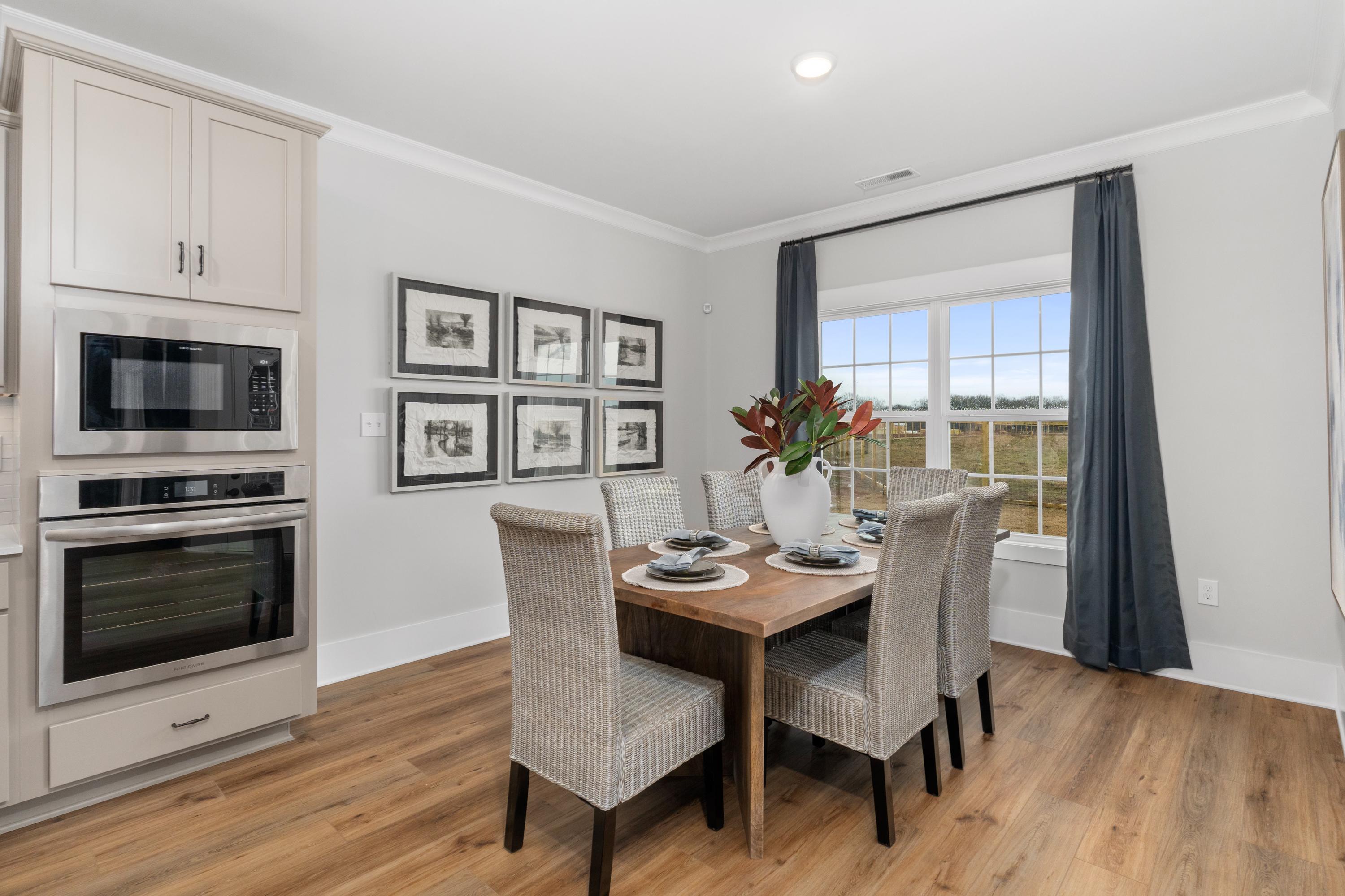 Elegant dining area in Kendall Farms home, Toney Alabama with shaker cabinets, stainless appliances, hardwood floors and scenic field view