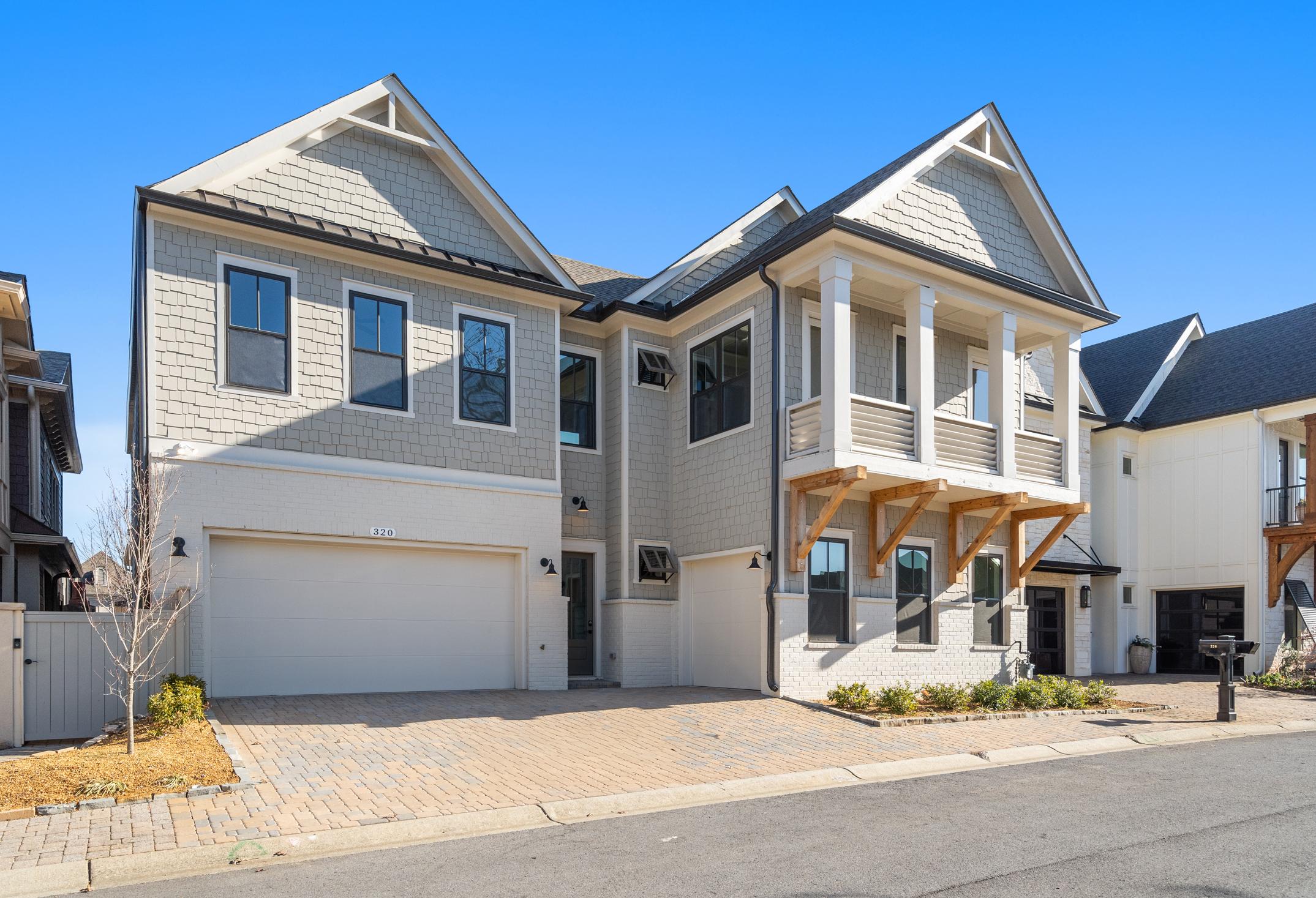 Modern two-story Seaside home exterior with gray siding, gabled roofs, balcony, and three-car garage in Woodstock, GA