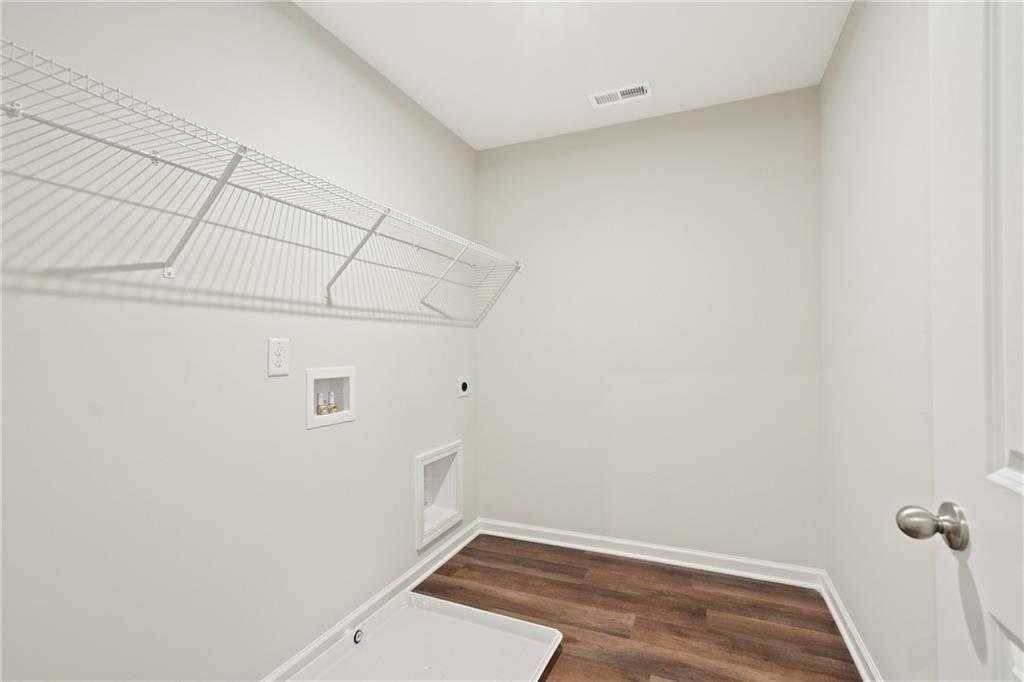 Bright laundry room with wire shelving, washer dryer hookups, hardwood floors in Davidson Homes The Cary B, Kennesaw, GA