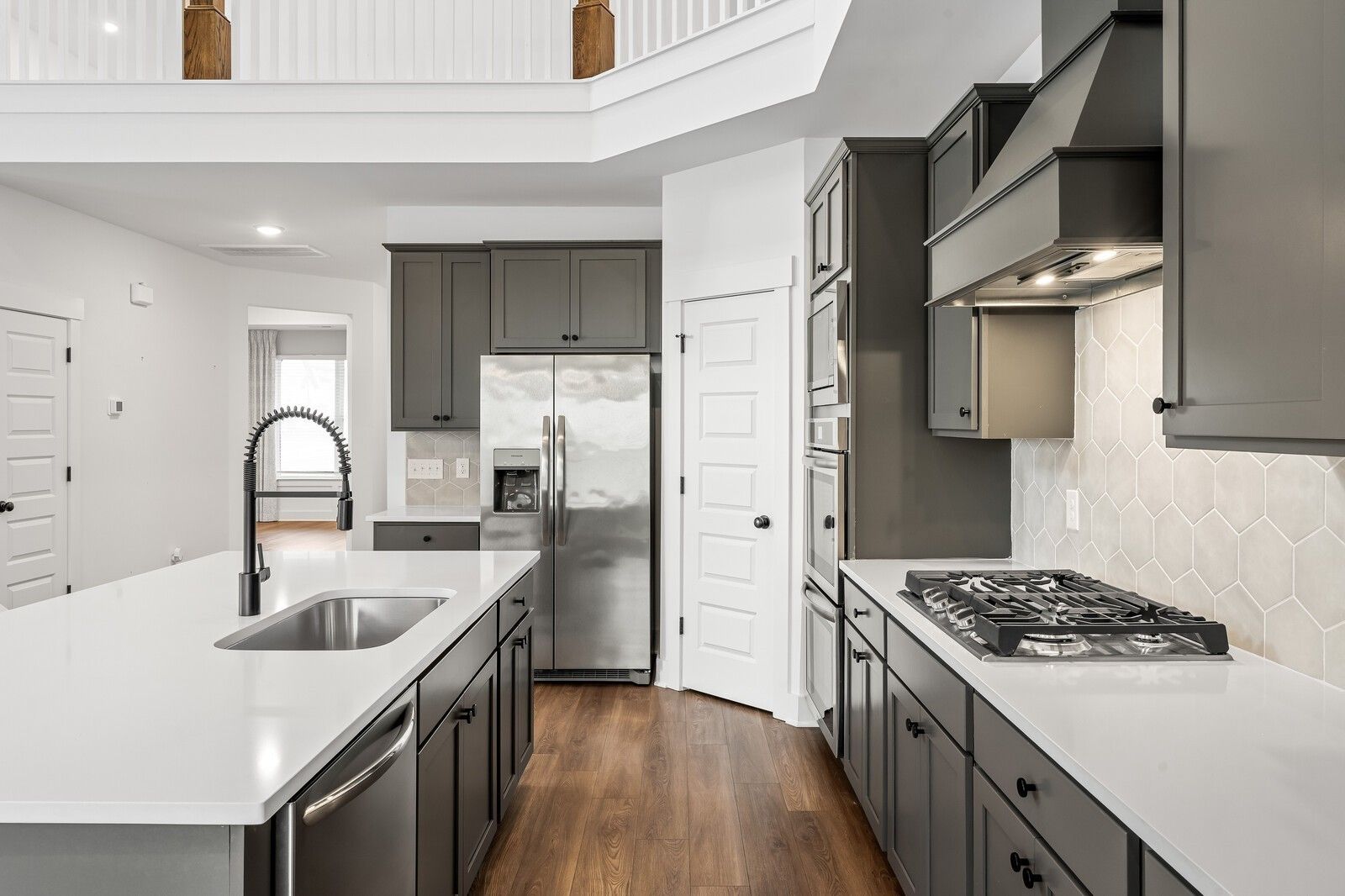 Modern open-concept kitchen with gray shaker cabinets, white quartz island, stainless appliances, and second-story overlook in The Ridgeport home, Gallatin, TN