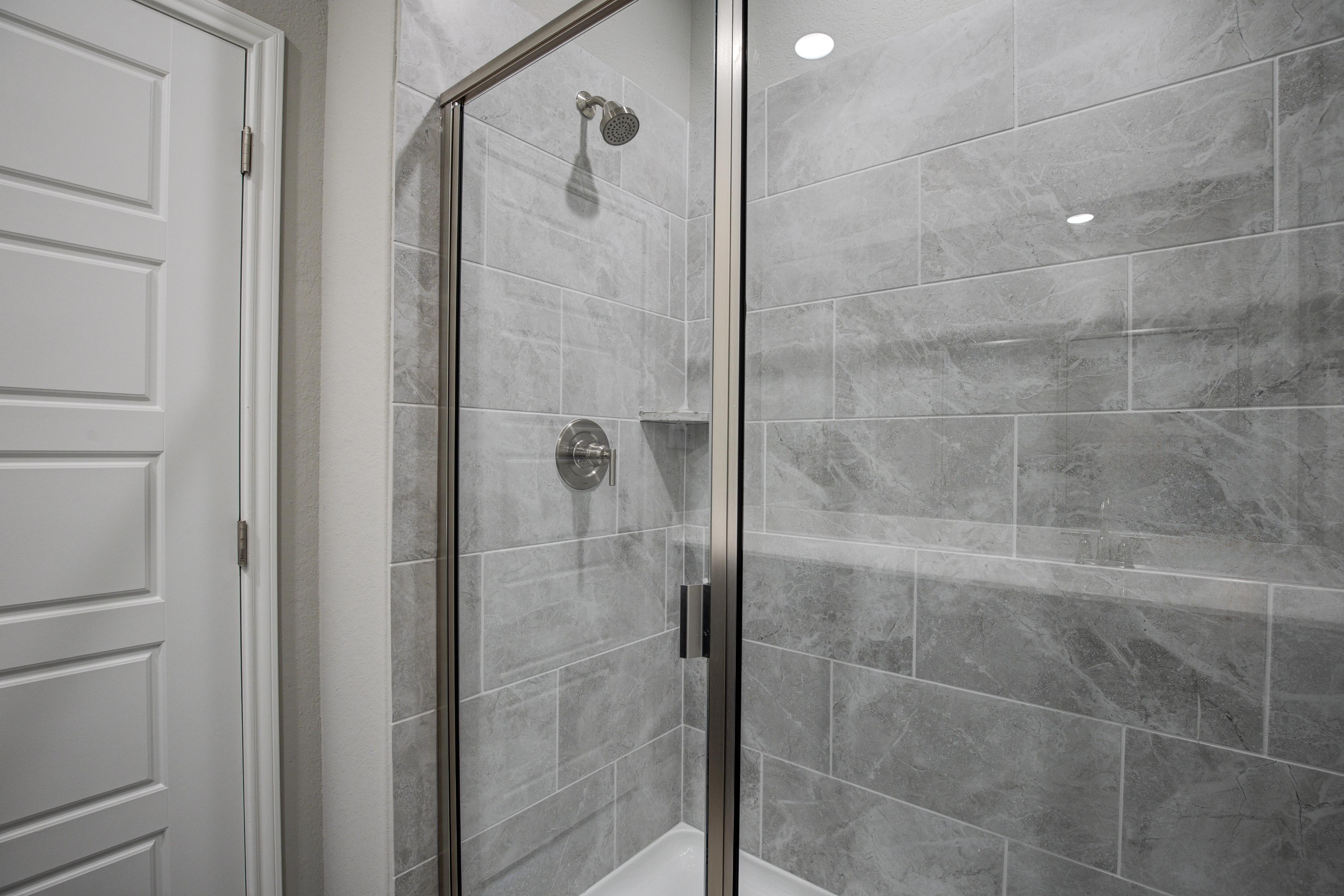 Modern walk-in shower in The Frio master suite with frameless glass enclosure and gray subway tiles