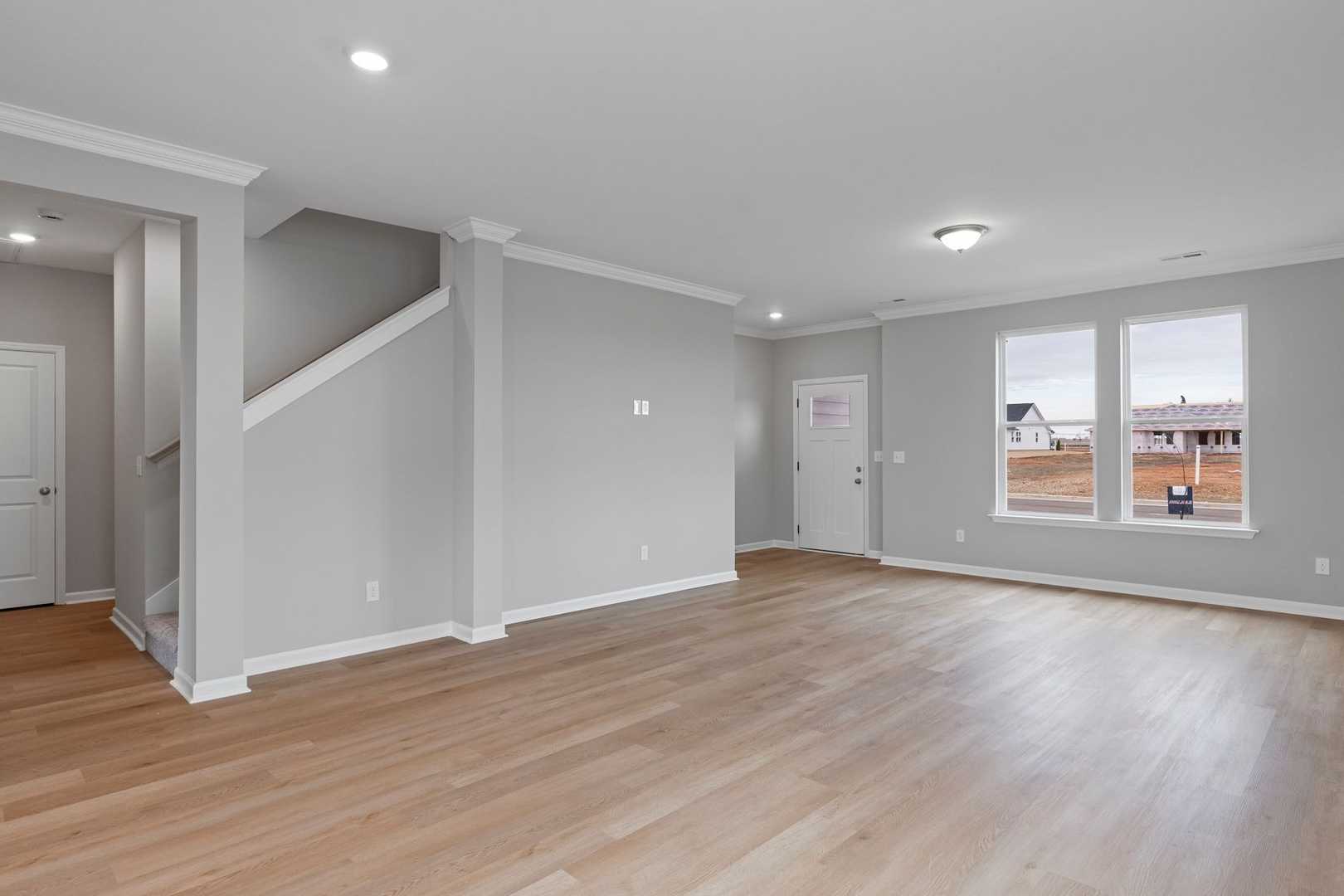 Spacious open floor plan in The Stella 2-story home with gray walls, hardwood floors, staircase, and large windows