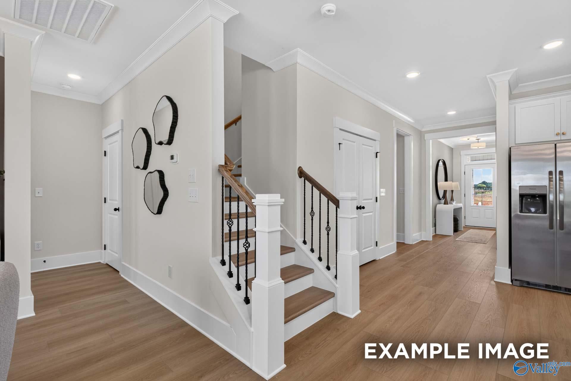 Foyer with hardwood floors, staircase with wrought iron balusters, and stainless refrigerator in Davidson Homes Ashport K, Hazel Green