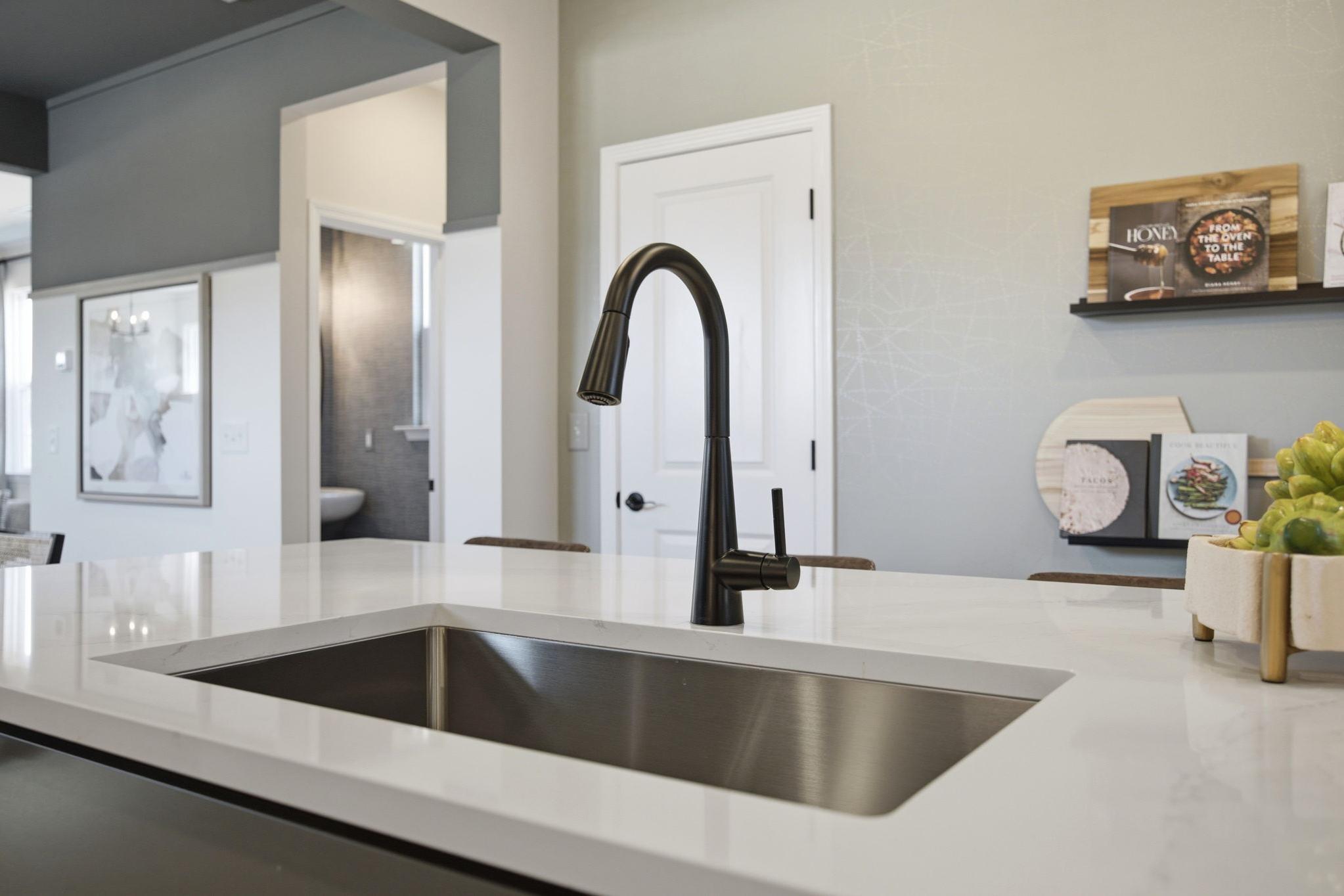 Modern kitchen island with undermount sink and matte black faucet in The Burke home design by Davidson Homes.