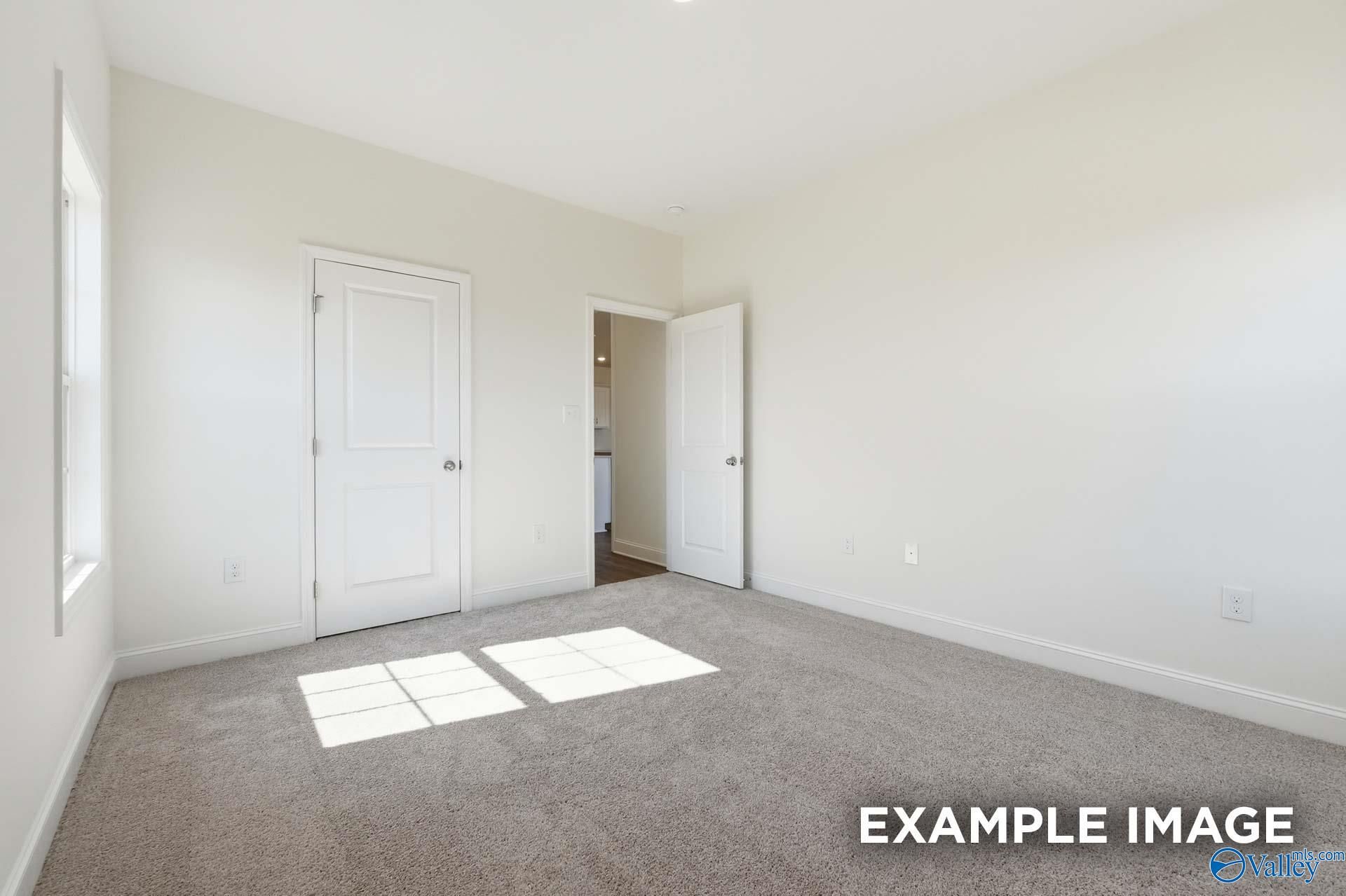 Bright, carpeted bedroom with white walls in The Valencia floor plan by Davidson Homes in Briercreek, Meridianville, AL.