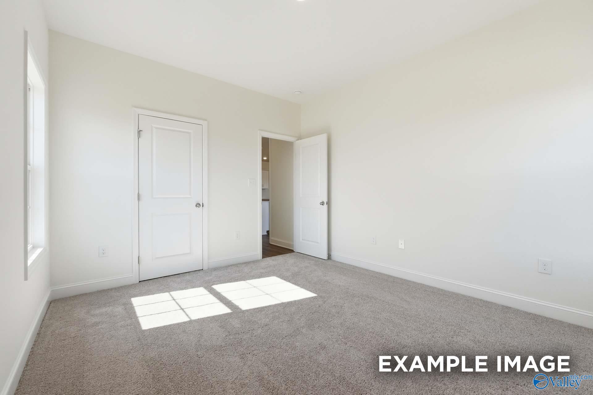 Bright, carpeted bedroom with white walls in The Valencia floor plan by Davidson Homes in Briercreek, Meridianville, AL.