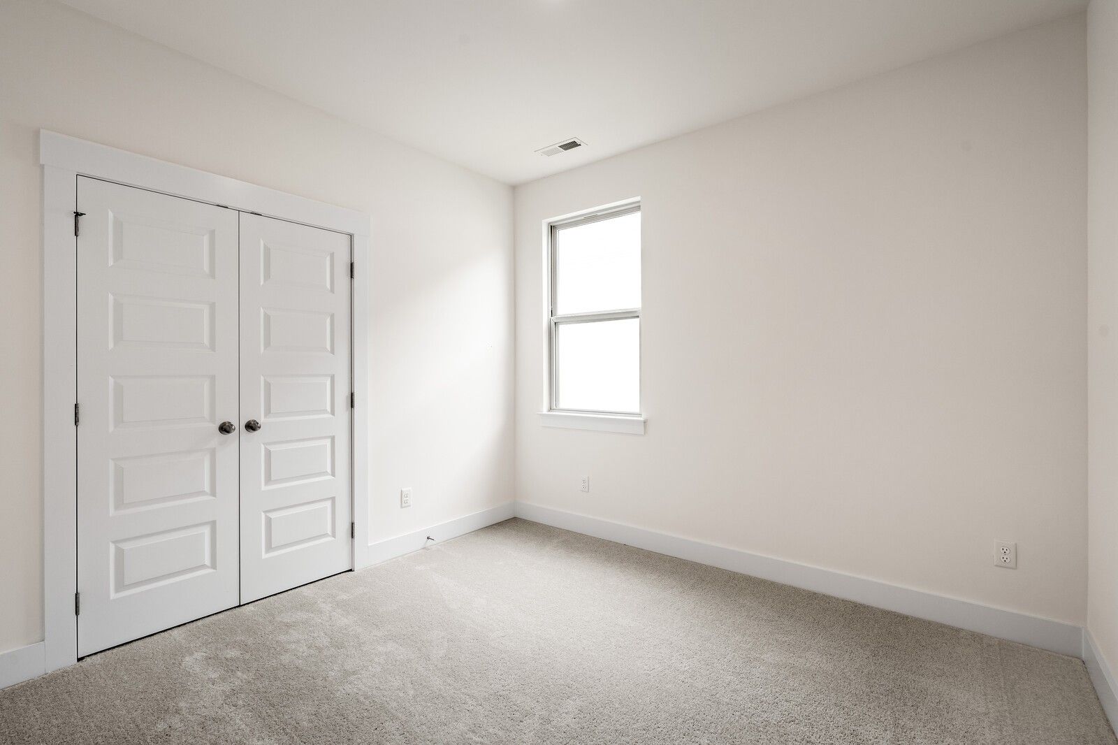 Bright bedroom with carpet and double-door closet in The Prairie C floor plan at Woods Crossing, Gallatin, Tennessee.