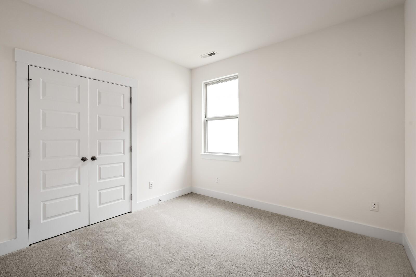 Bright bedroom with carpet and double-door closet in The Prairie C floor plan at Woods Crossing, Gallatin, Tennessee.