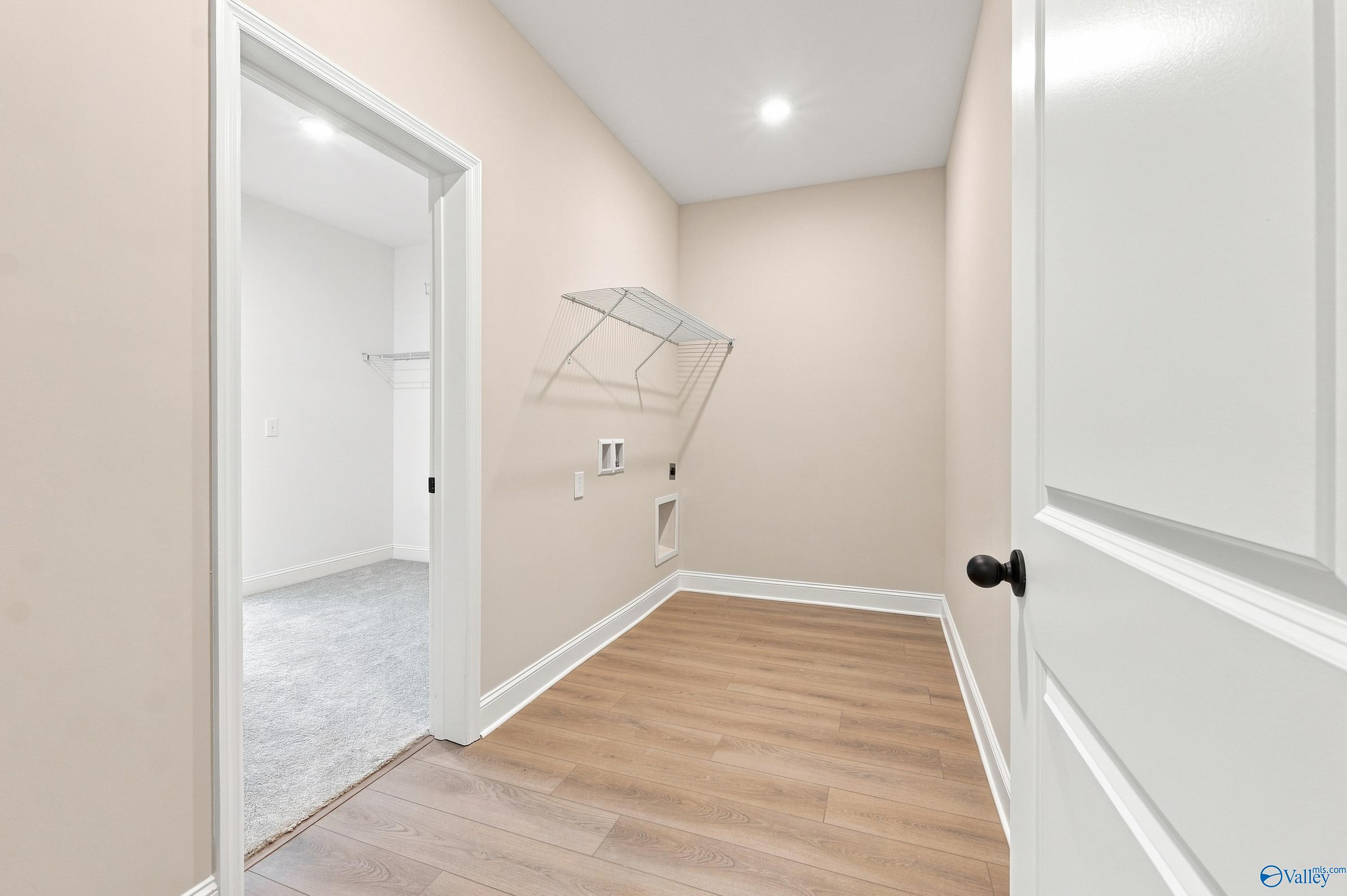 Laundry room with wire shelving and wood-look floors in The Rockford B floor plan at Kendall Downs in Toney, Alabama.