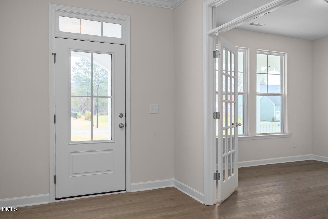 Welcoming entryway with white glass-paneled front door, open French doors, hardwood floors in 4-bedroom Cypress D II home, Angier NC