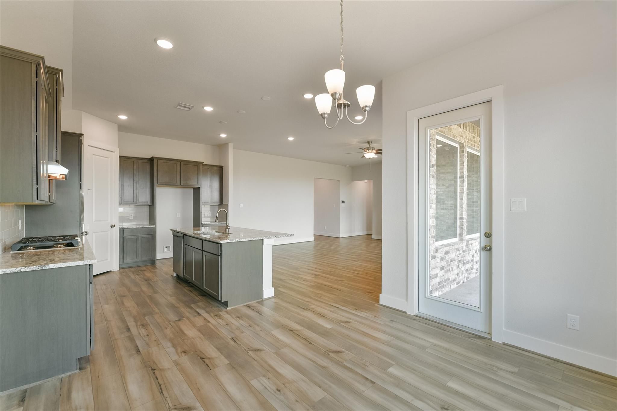 Modern open-concept kitchen with gray shaker cabinets, quartz island, and French doors to patio in Davidson Homes The Edward A, Lago Mar
