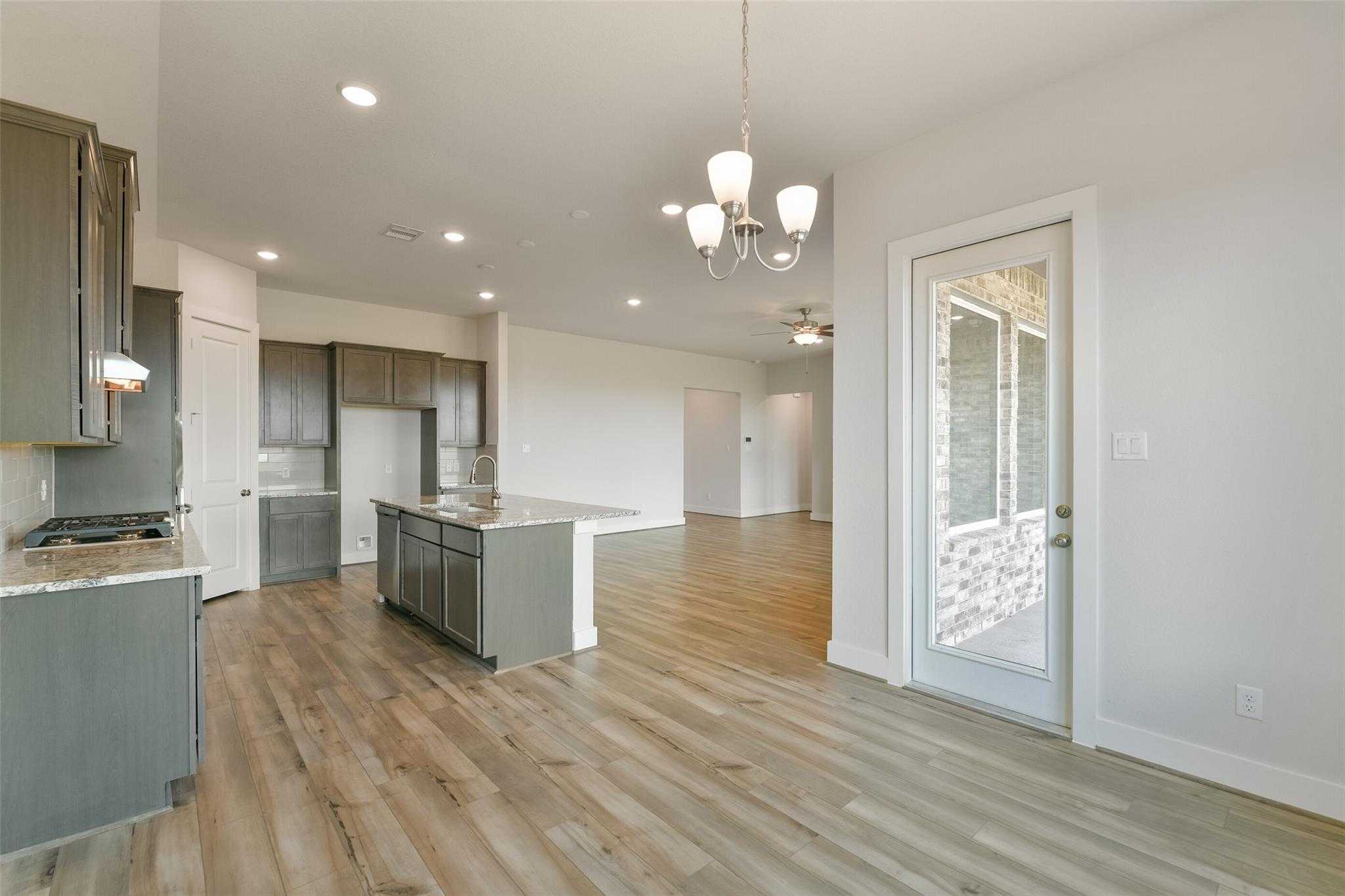 Modern open-concept kitchen with gray shaker cabinets, quartz island, and French doors to patio in Davidson Homes The Edward A, Lago Mar