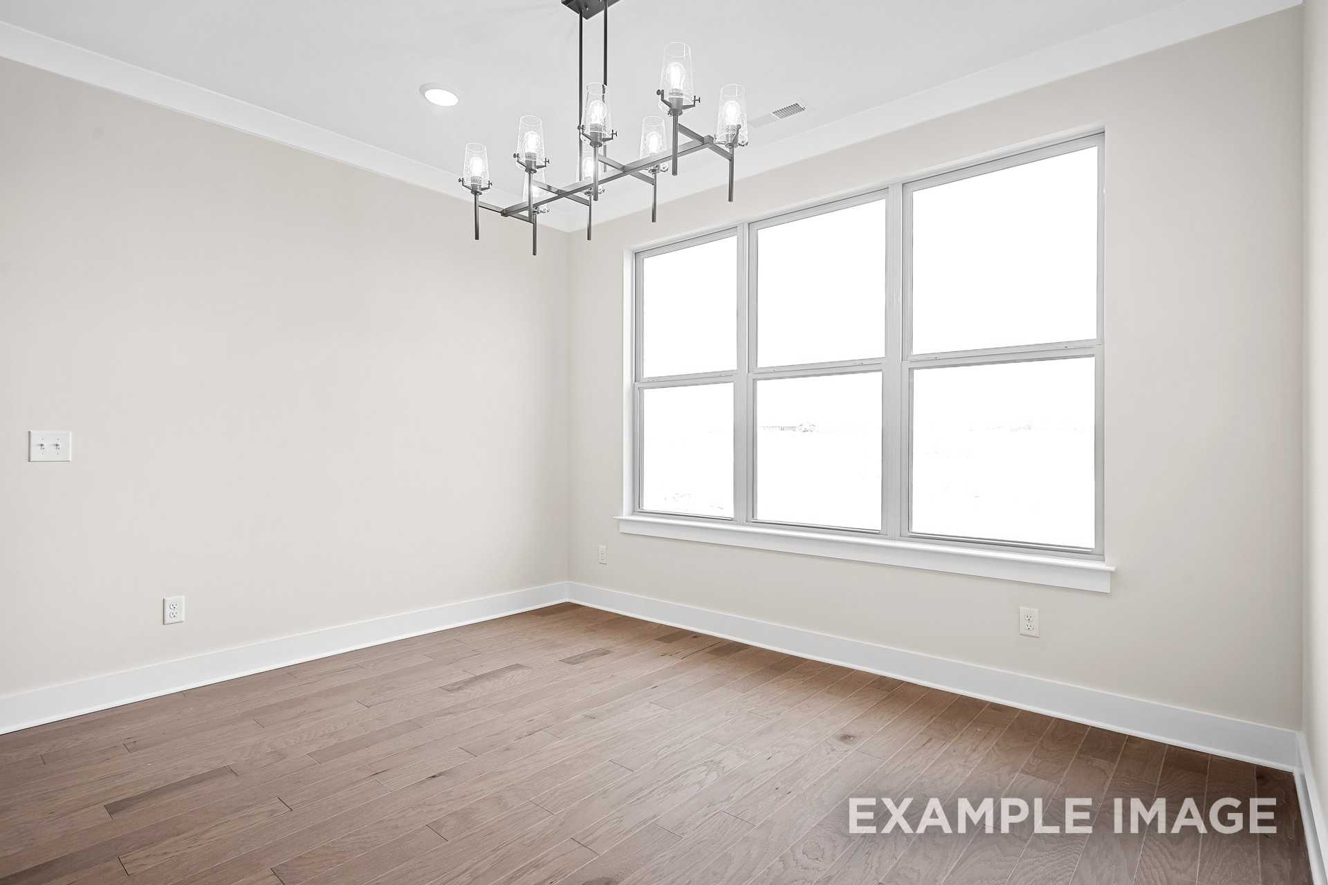 Spacious dining room in The Hawkins home design featuring hardwood floors, neutral walls, large windows, and modern chandelier