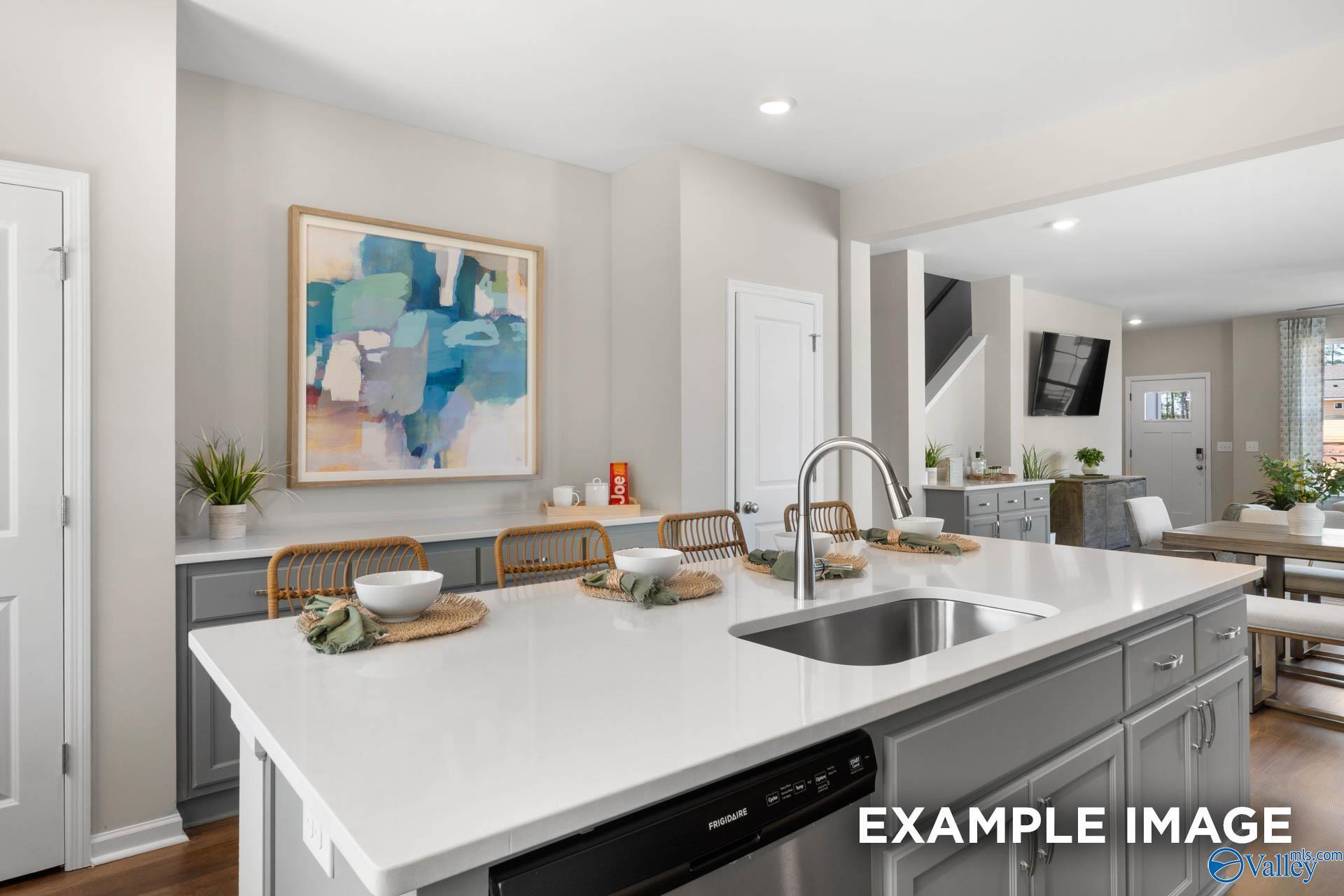 Open-concept kitchen with white quartz island, gray cabinets, stainless sink, and abstract art in Davidson Homes The Stella, Madison AL
