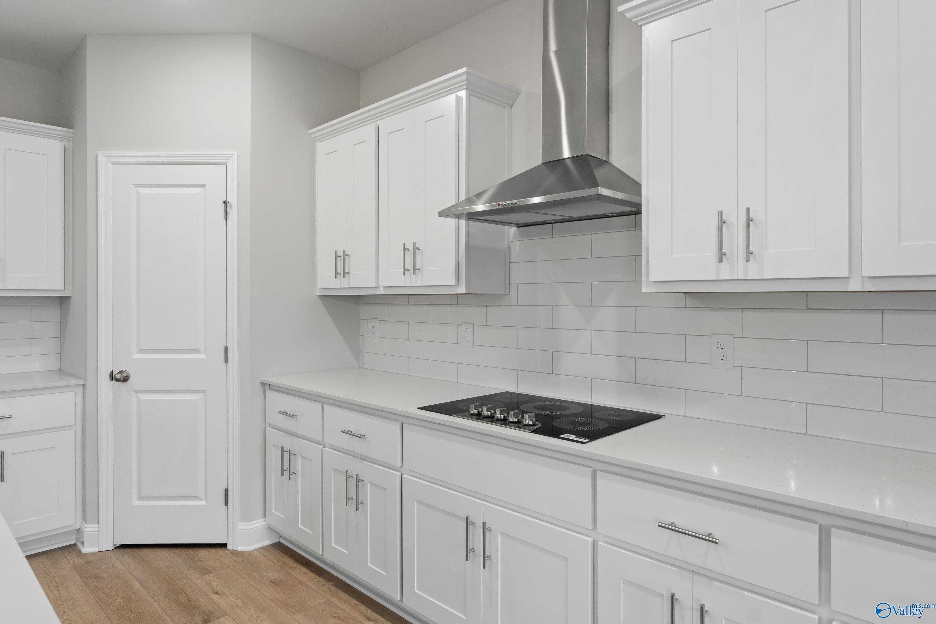 Modern white shaker kitchen with stainless range hood, gas cooktop, subway tile backsplash in Davidson Homes The Rockford B, Toney, Alabama