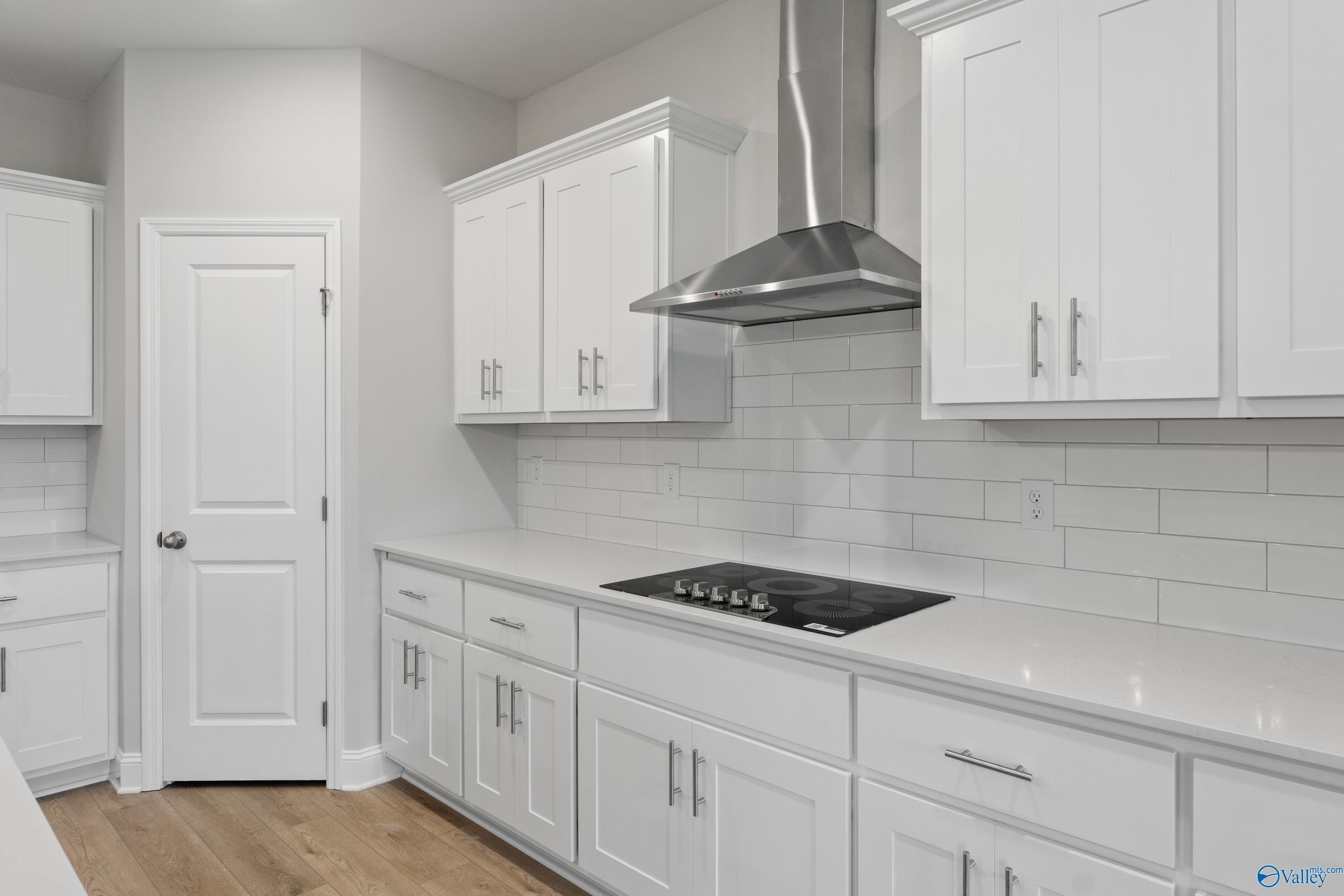 Modern white kitchen with shaker cabinets, stainless range hood, gas cooktop, subway tile backsplash in Davidson Homes The Rockford B, Toney, AL