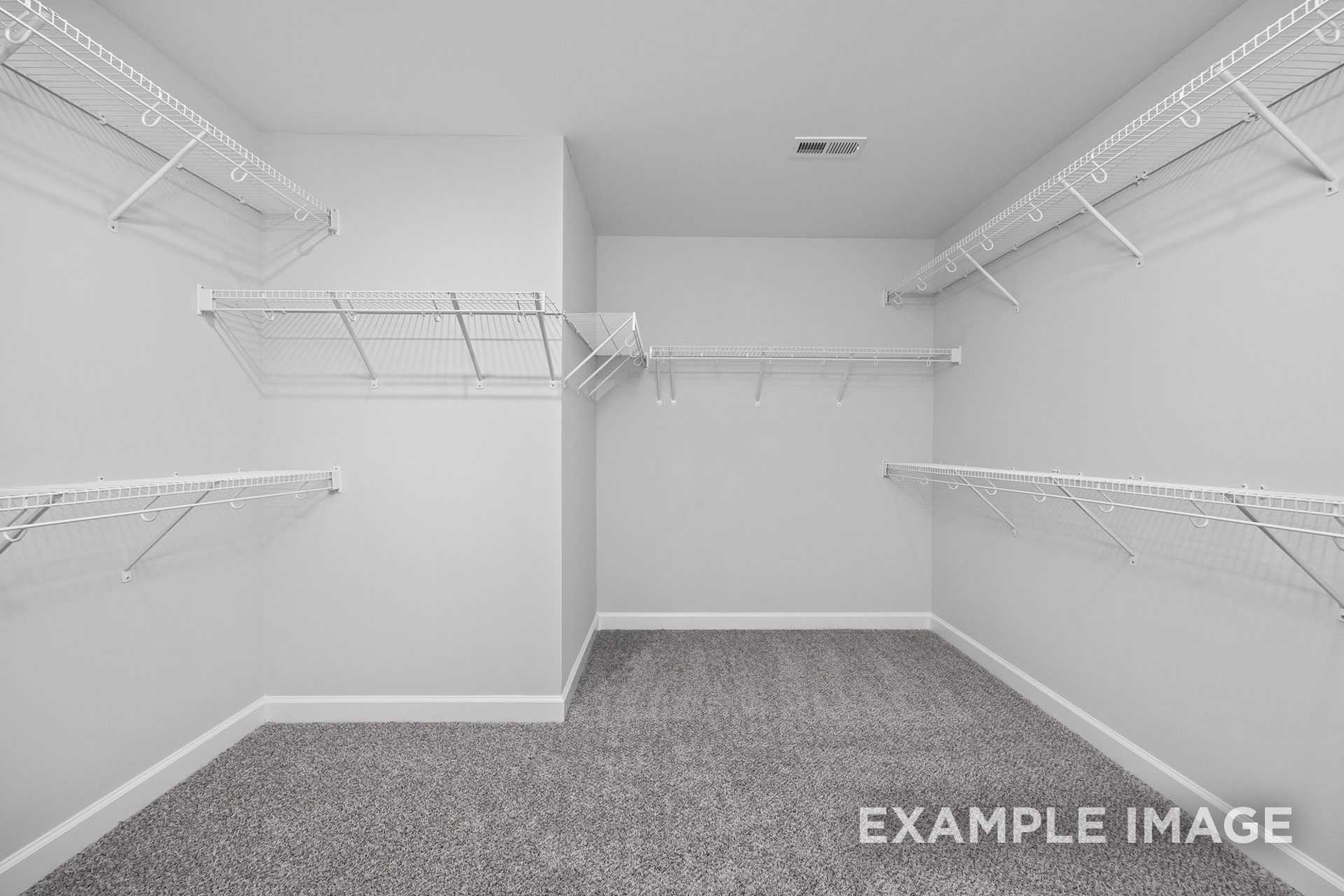 Spacious walk-in closet in The Preston B master suite featuring white wire shelving and gray carpet flooring