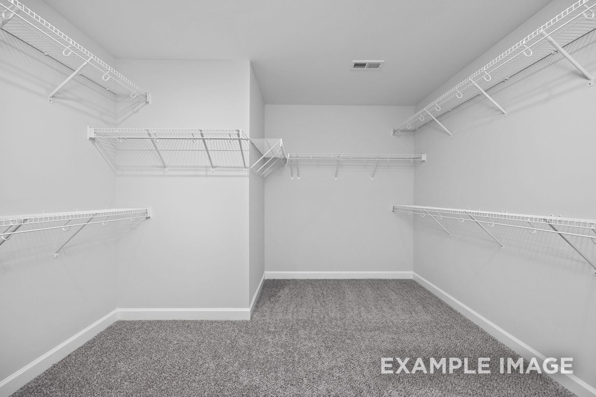 Spacious walk-in closet in The Preston B master suite featuring white wire shelving and gray carpet flooring