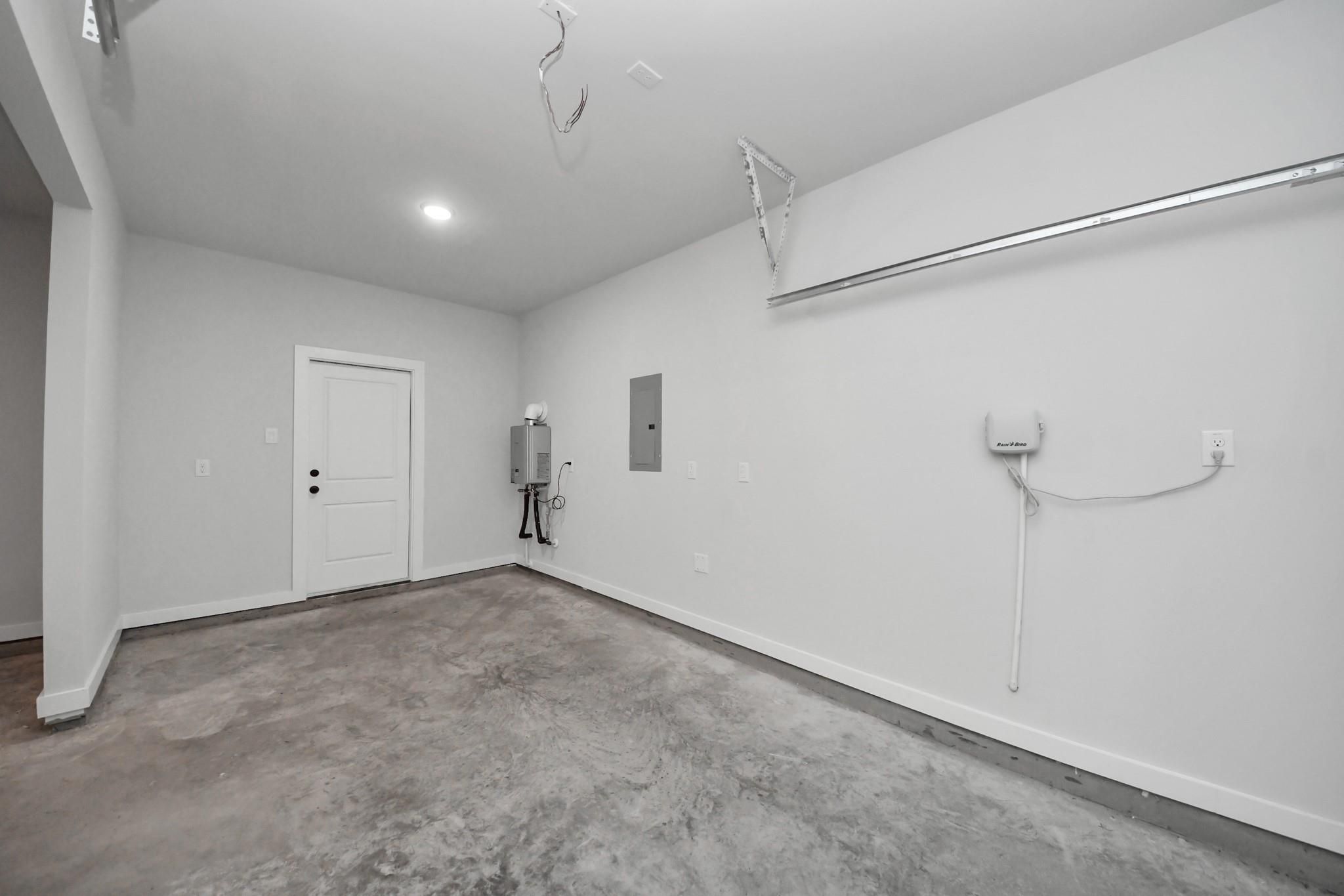 Spacious 3-car garage with tankless water heater and entry door in Davidson Homes The Riviera C, River Ranch Meadows, Dayton, Texas