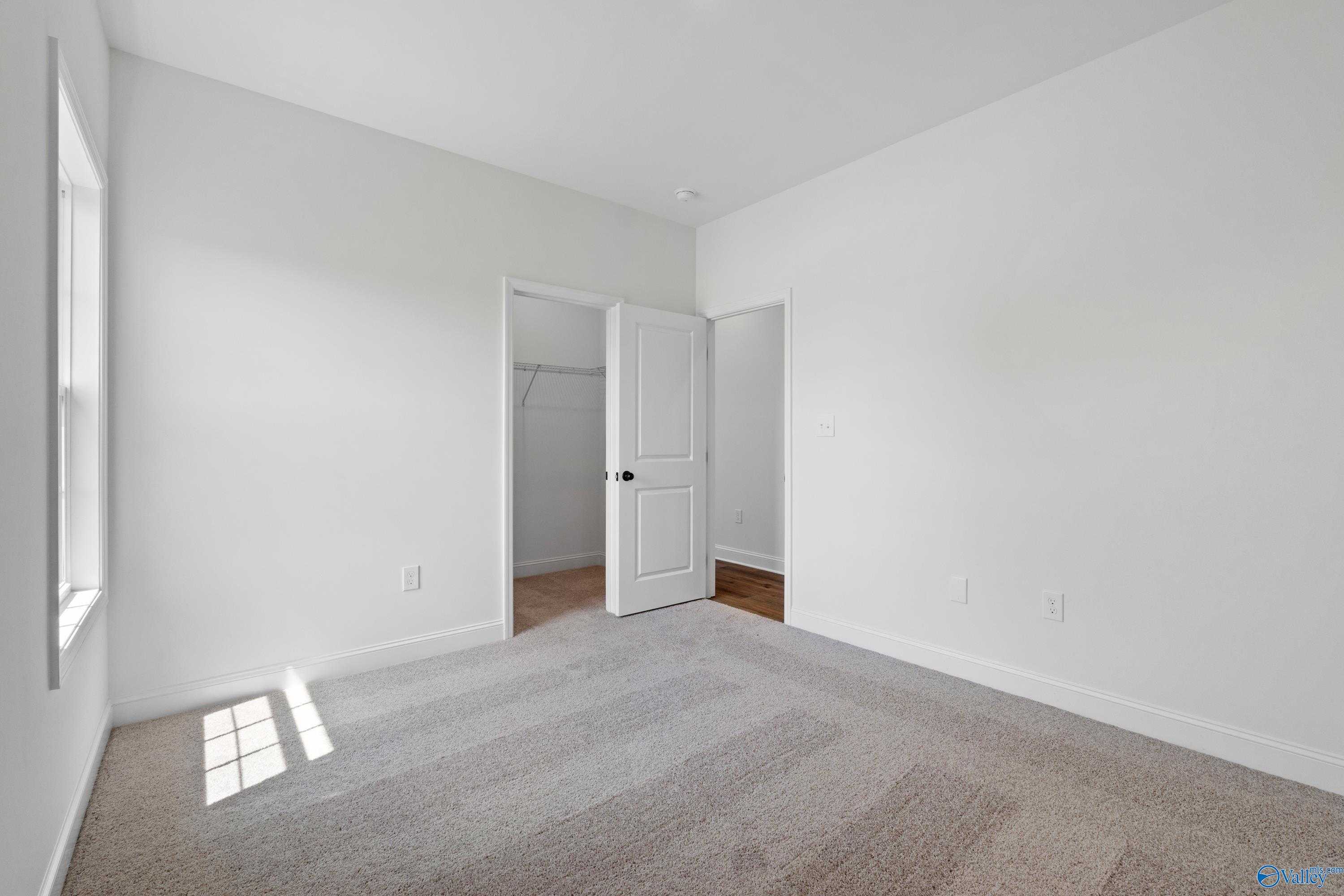 Bright secondary bedroom with white walls, carpet flooring, and open closet door in Davidson Homes The Rockford B, Toney, Alabama