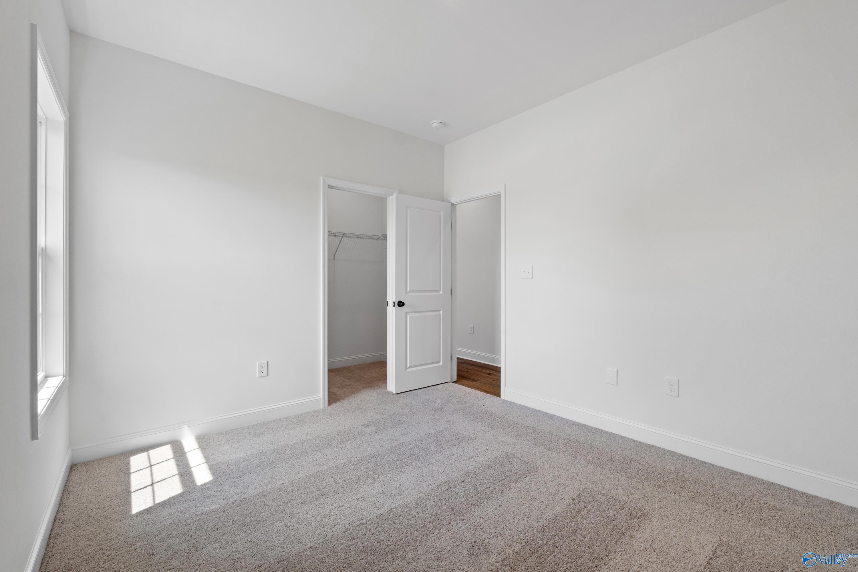 Bright secondary bedroom with open walk-in closet, carpeted floor, and natural light in Davidson Homes The Rockford B, Toney, Alabama