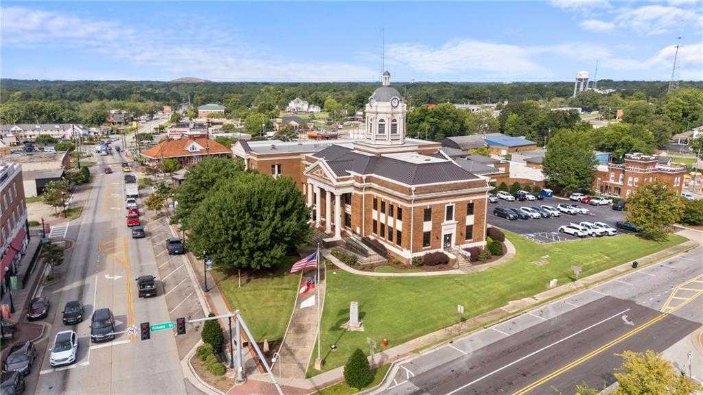 Aerial view of historic red brick courthouse with clock tower and American flag in downtown Winder, Georgia, near Lake Shore homes