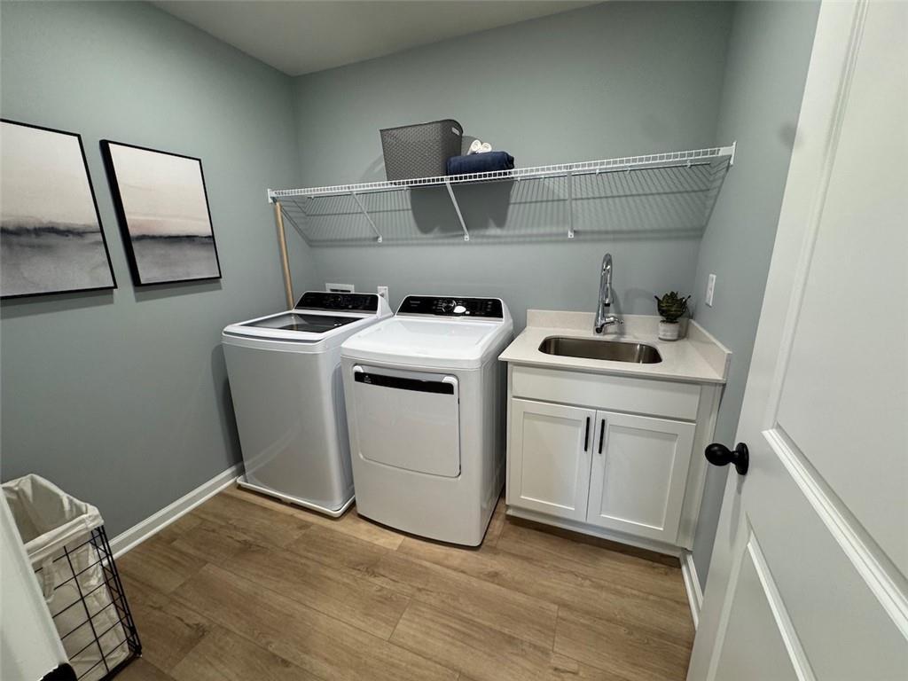 Modern laundry room with white washer, dryer, utility sink, and storage shelves in Davidson Homes The Hartwell A, Canton, Georgia