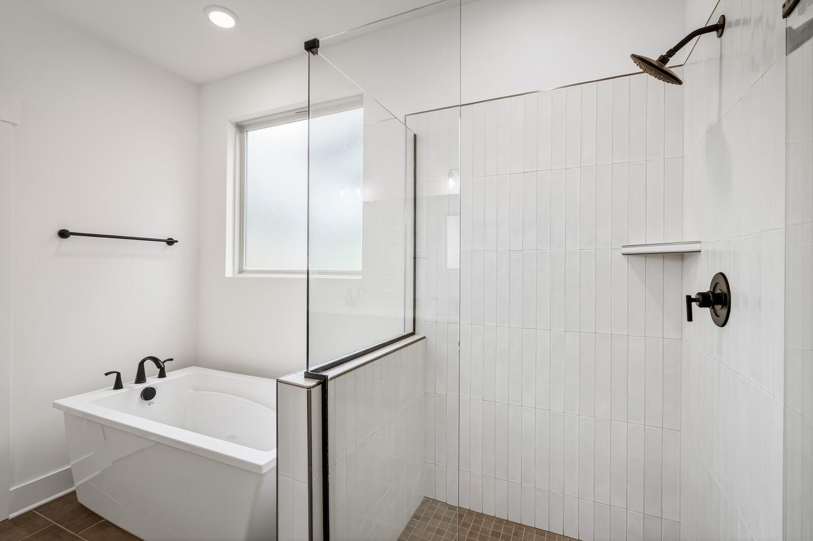 Modern master bathroom with glass-enclosed white tile shower and freestanding soaking tub in Davidson Homes The Ridgeport C, Gallatin, TN