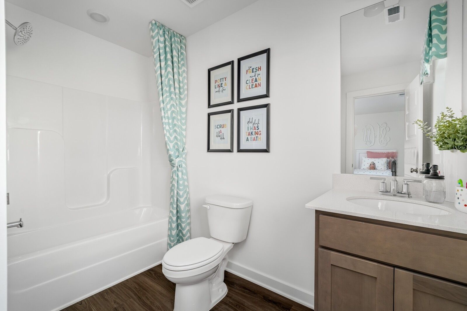 Bright bathroom with polka-dot shower curtain, white tub, wooden vanity in Davidson Homes Cumberland A, Gallatin TN