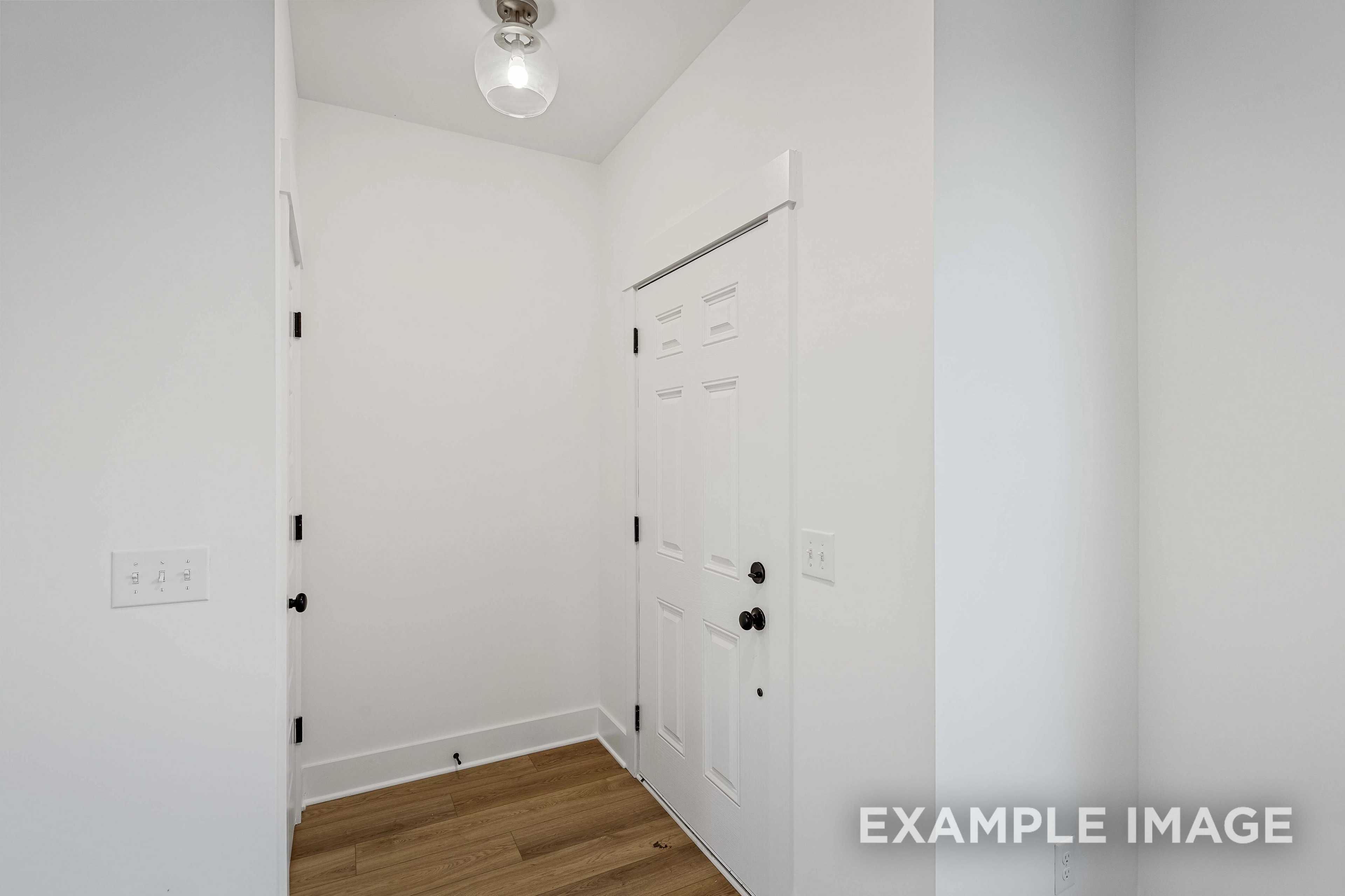 Spacious entry foyer in The Charleston Davidson Homes design with white paneled doors, hardwood floors, and coat closet