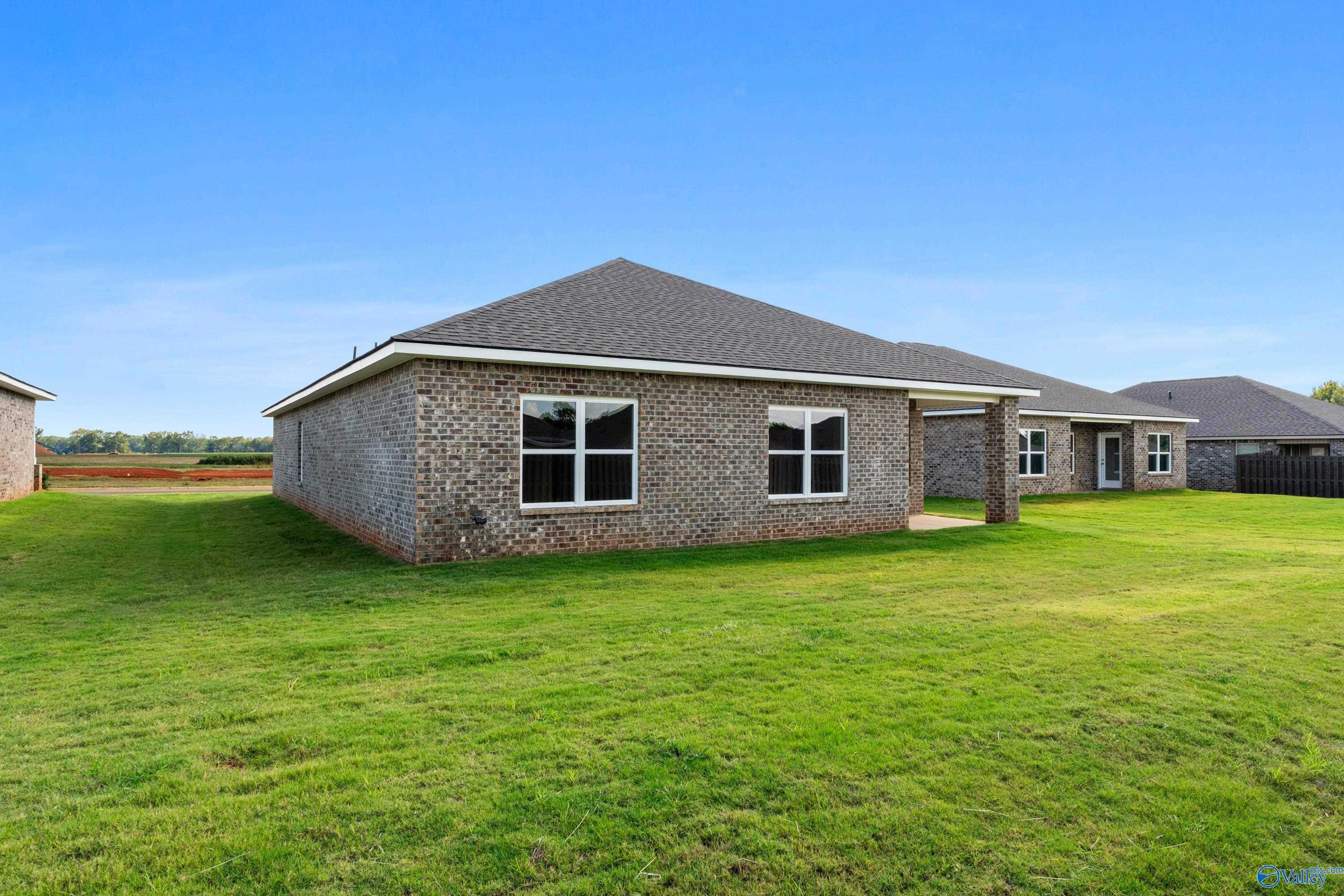 Single-story brick Daphne home with covered patio, large windows, and lush green yard in Clearview, Hazel Green, Alabama