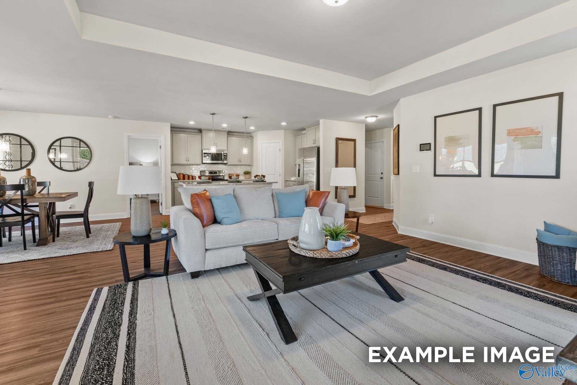 Open-concept living room with white sofa, coffee table, dining area, and kitchen in The Franklin C by Davidson Homes, New Market, Alabama