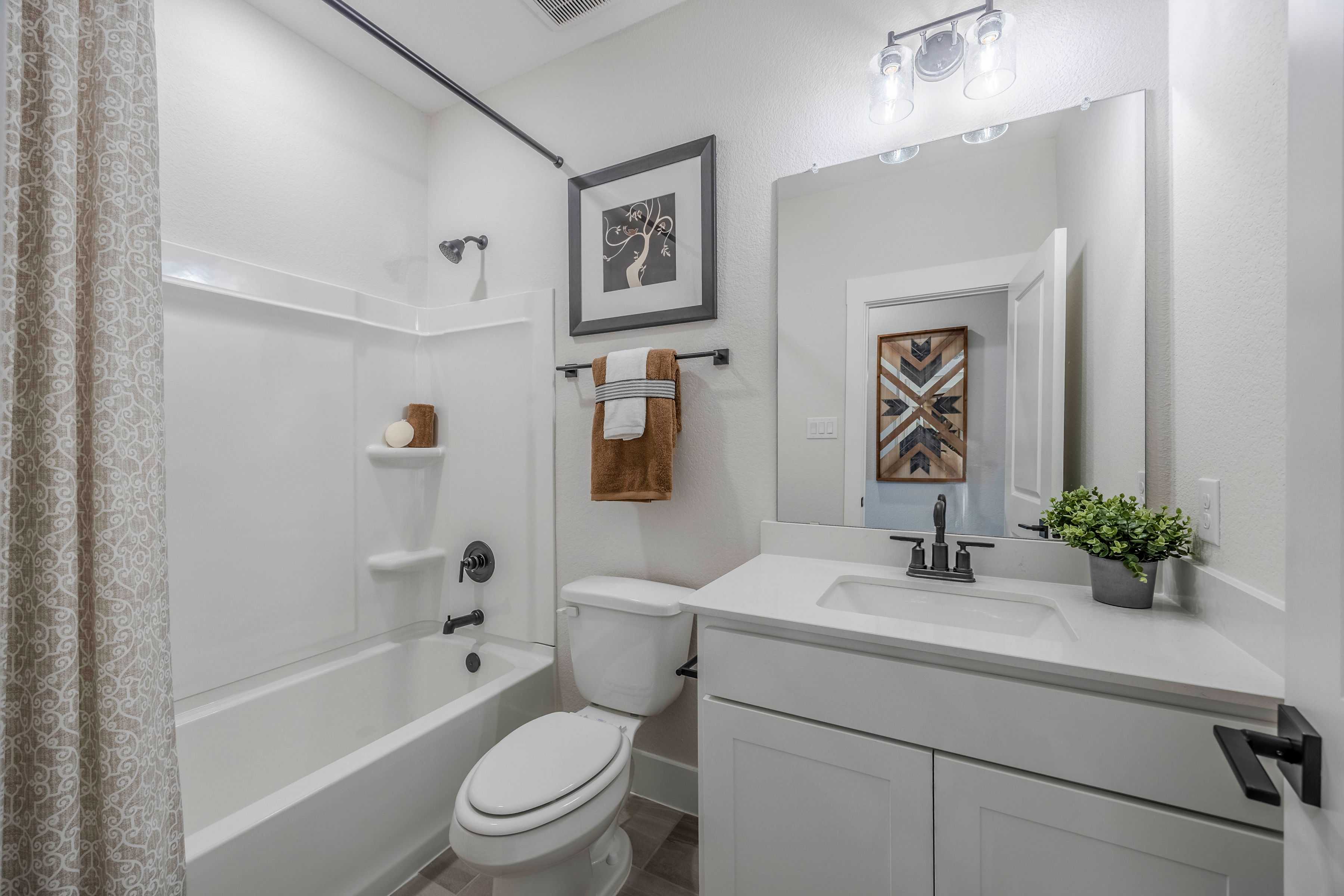 Spacious master bathroom in The Rockford with white tub, vanity sink, large mirror, and modern fixtures